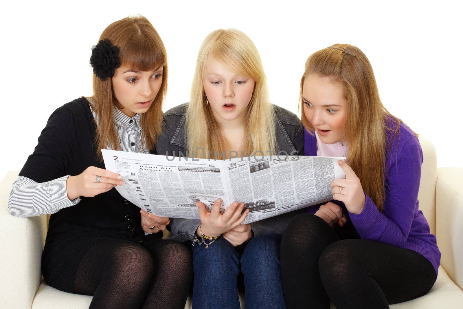 Three young girls are reading a newspaper on white
