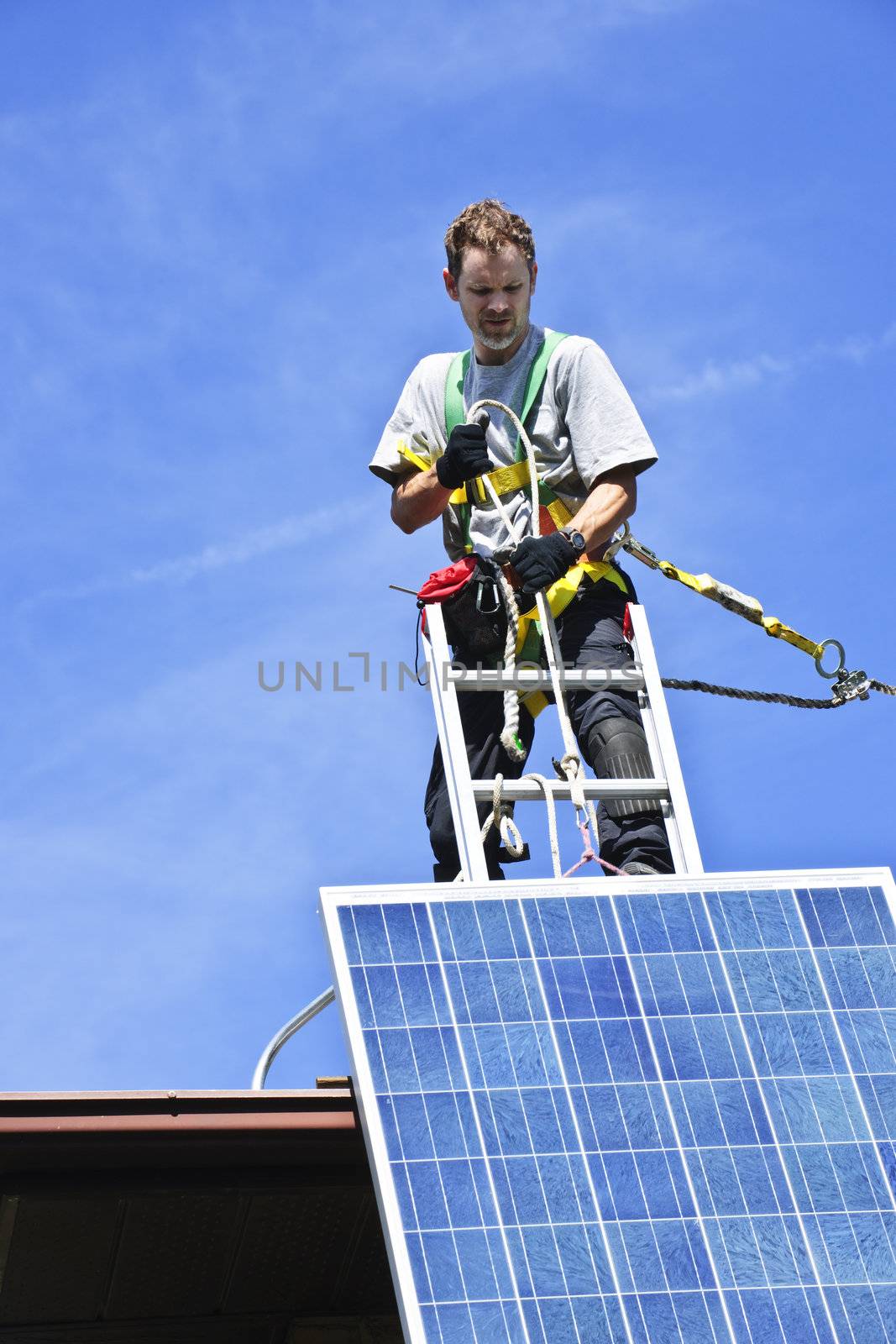 Man installing alternative energy photovoltaic solar panels on roof