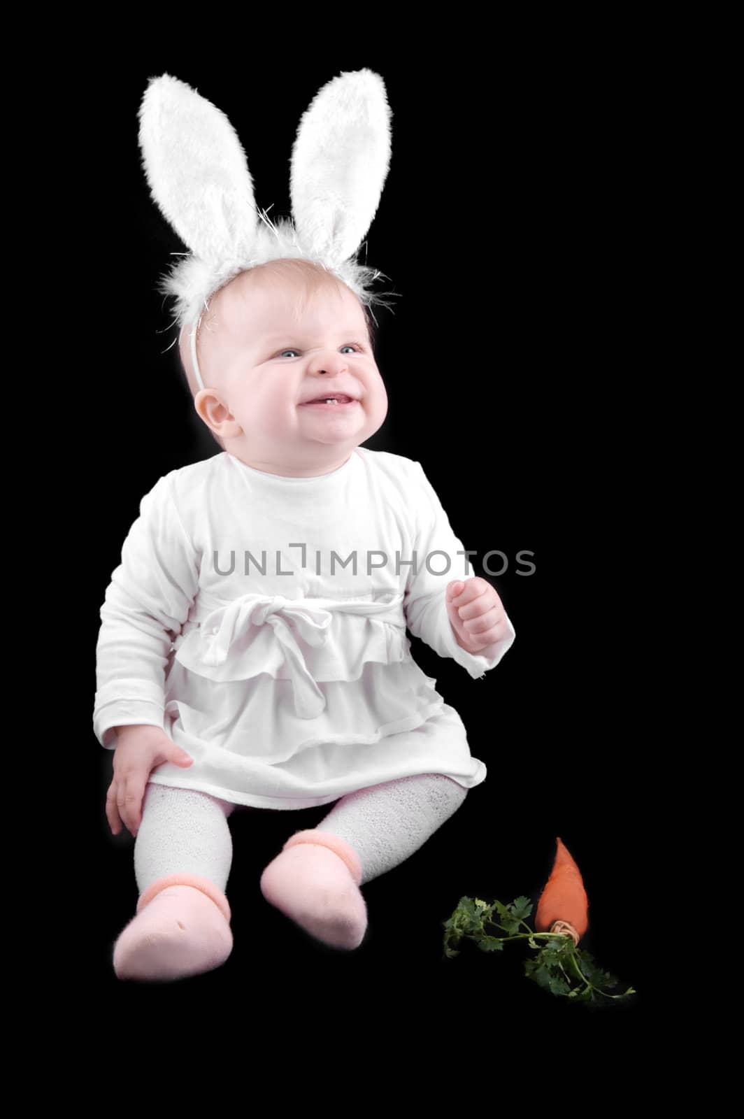Funny baby in bunny costume and carrot on black