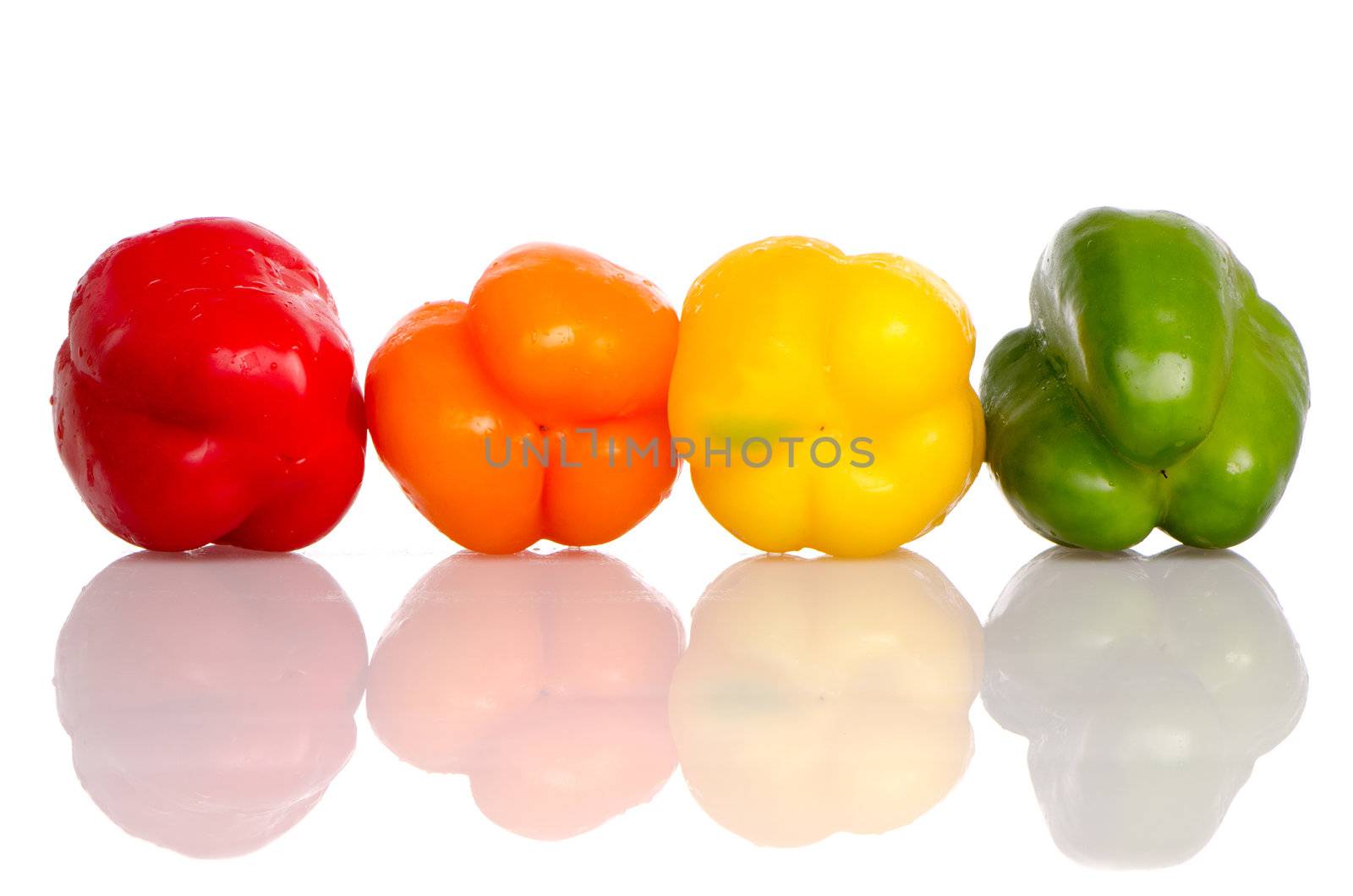 Colorful fresh mixed bell peppers on white reflective background.