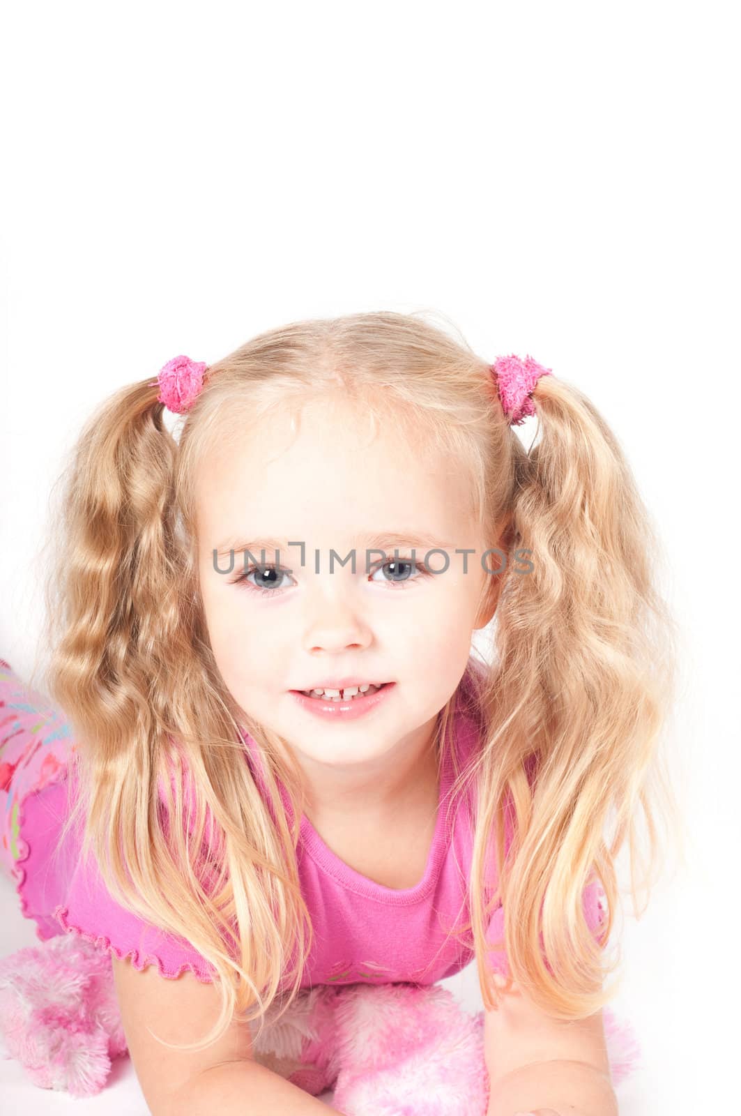 Little cute girl in pink and with ponytails in studio