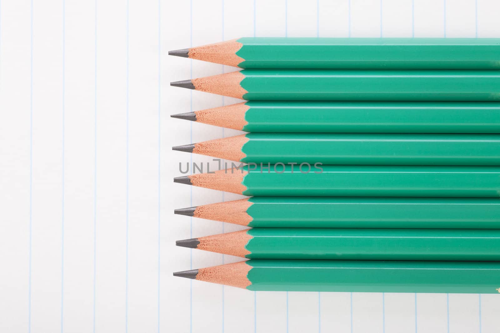 Eight green pencils on notebook paper.