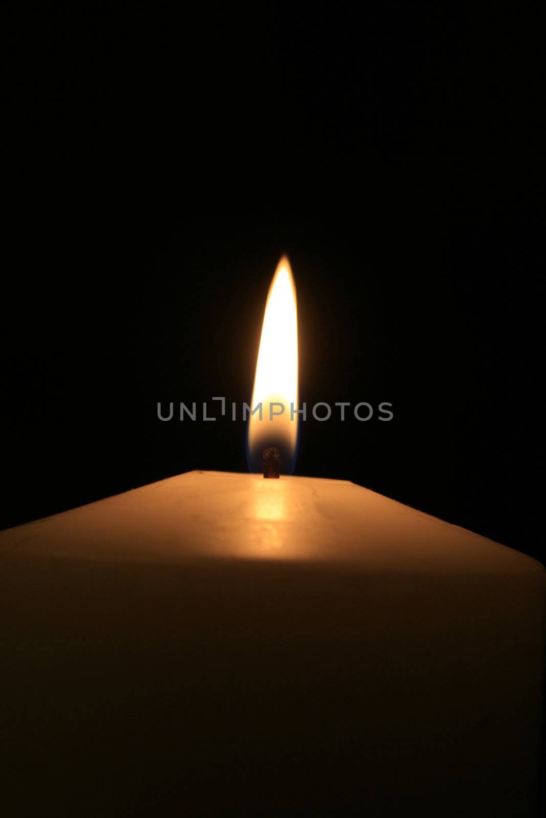 a white burning candle with black background