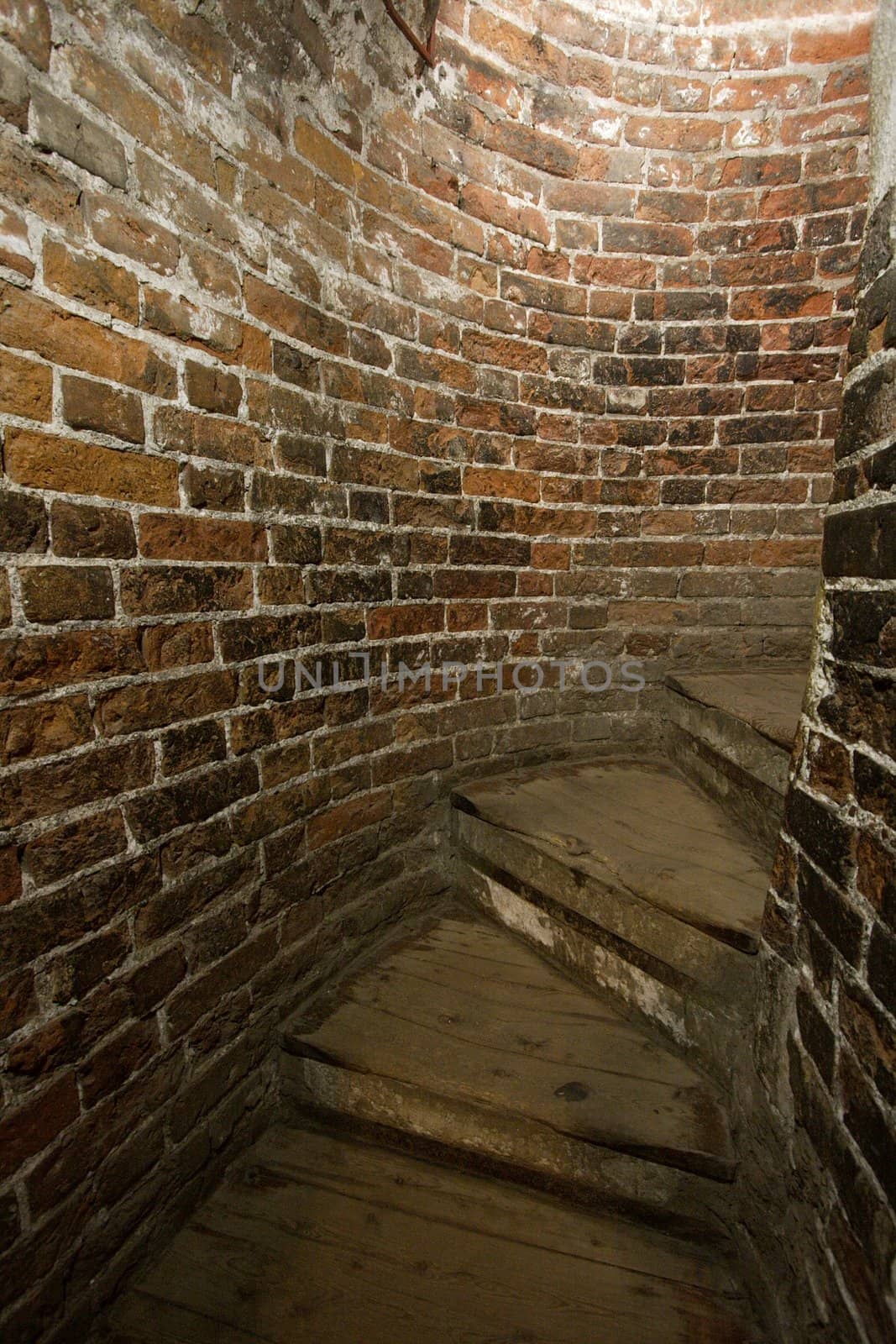 Old staircase in a tight corridor with old brick walls