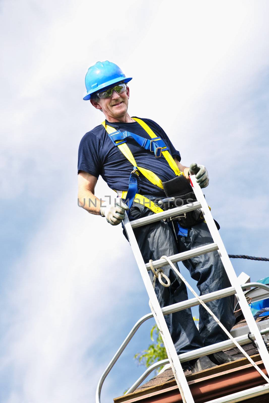 Construction worker standing on roof near ladder