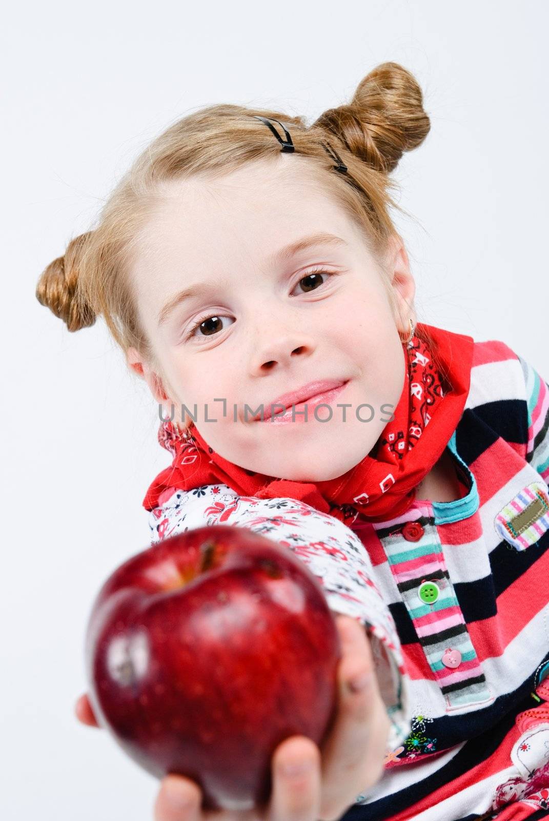 studio shot of pretty little girl offering a red apple