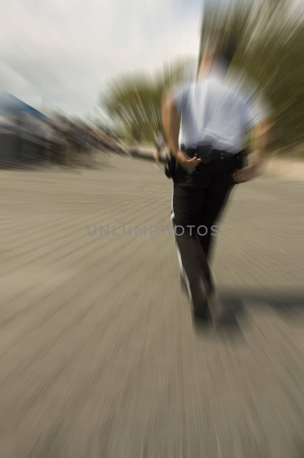 running policeman reaching for his handcuffs, motion blur