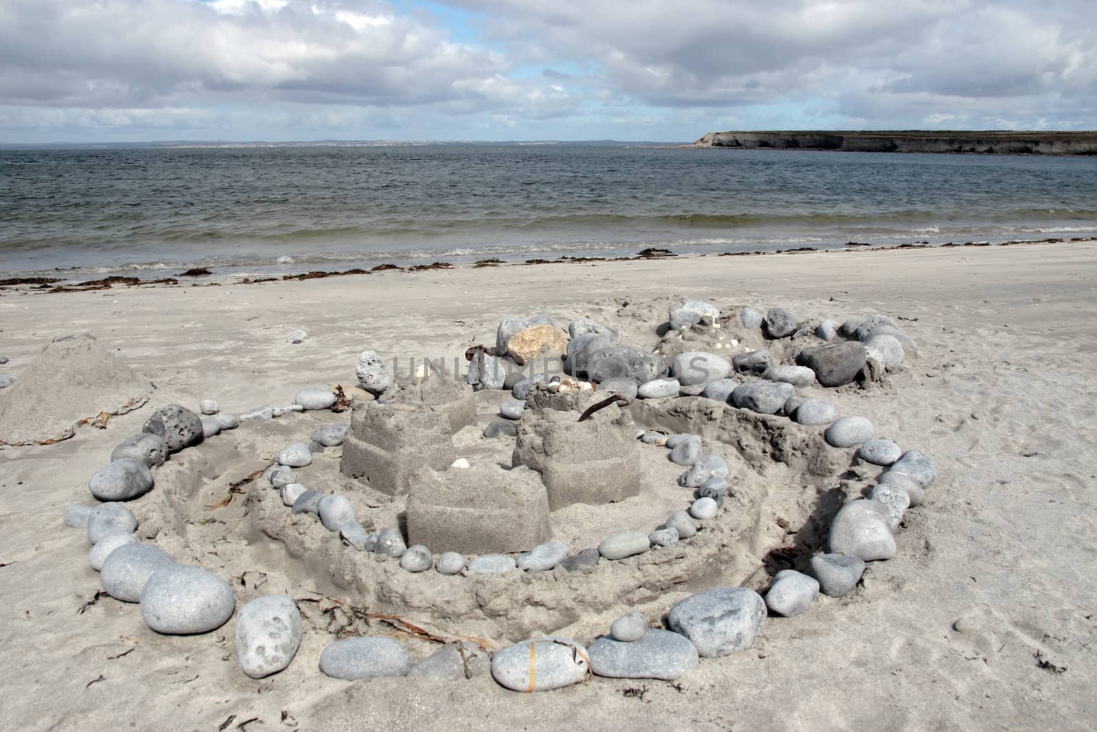 a sandcastle made with stones and sand on an irish shore