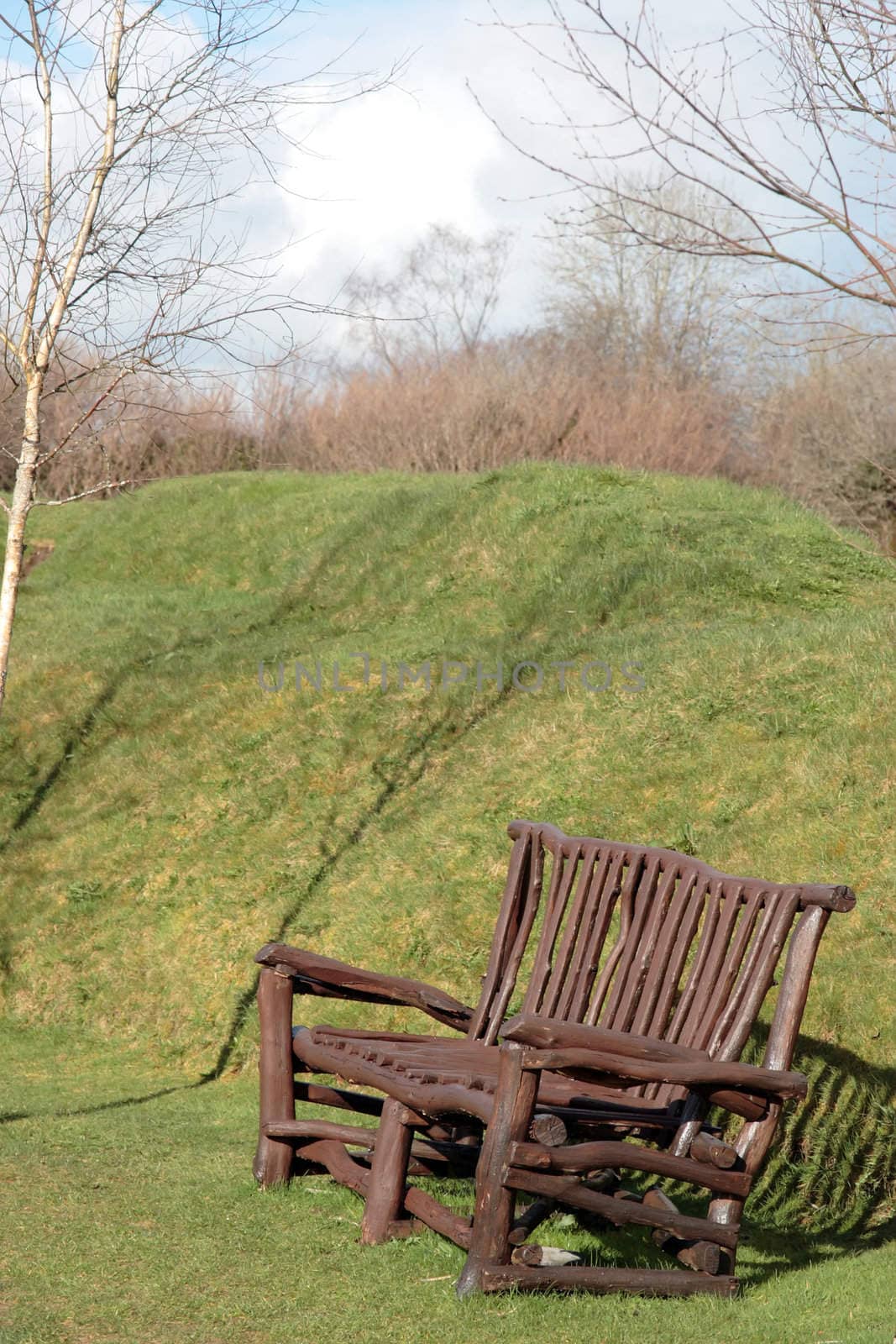 a solid wood park bench in grass surroundings