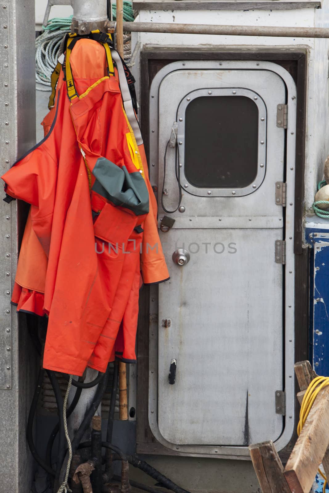 waterproof storm jackets and bibs hanging on fishing boat