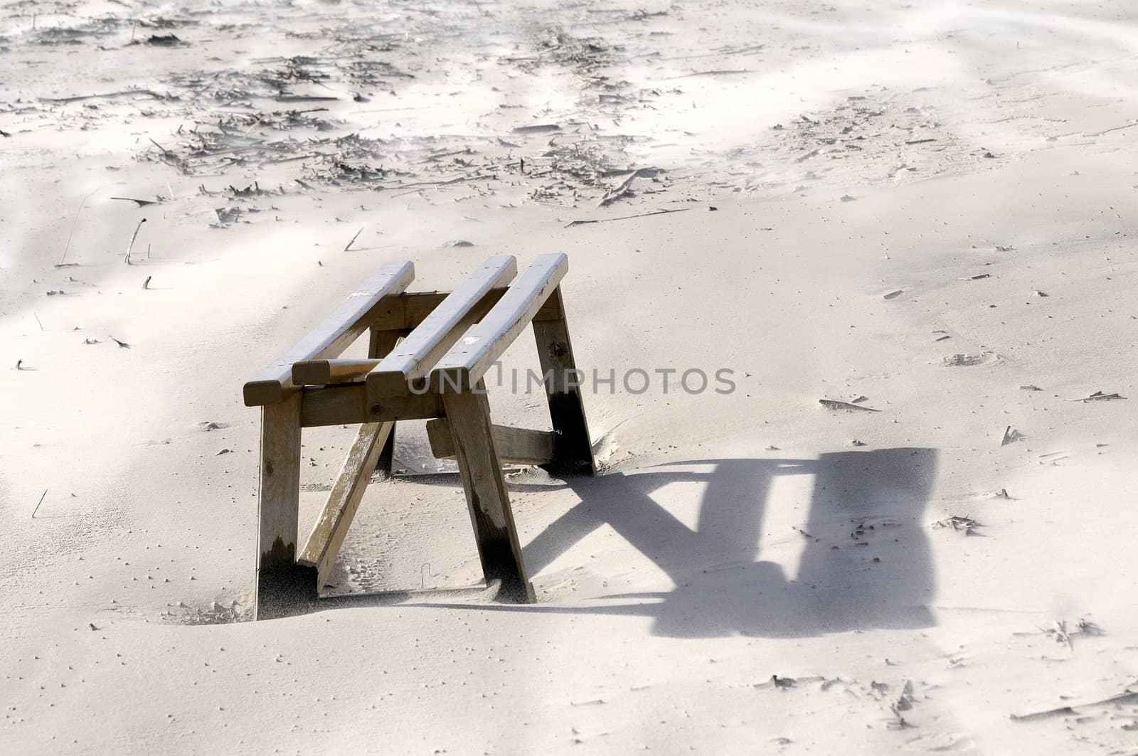 Broken wooden bench in Baltic sea beach. Windy day. The wind blows off sand