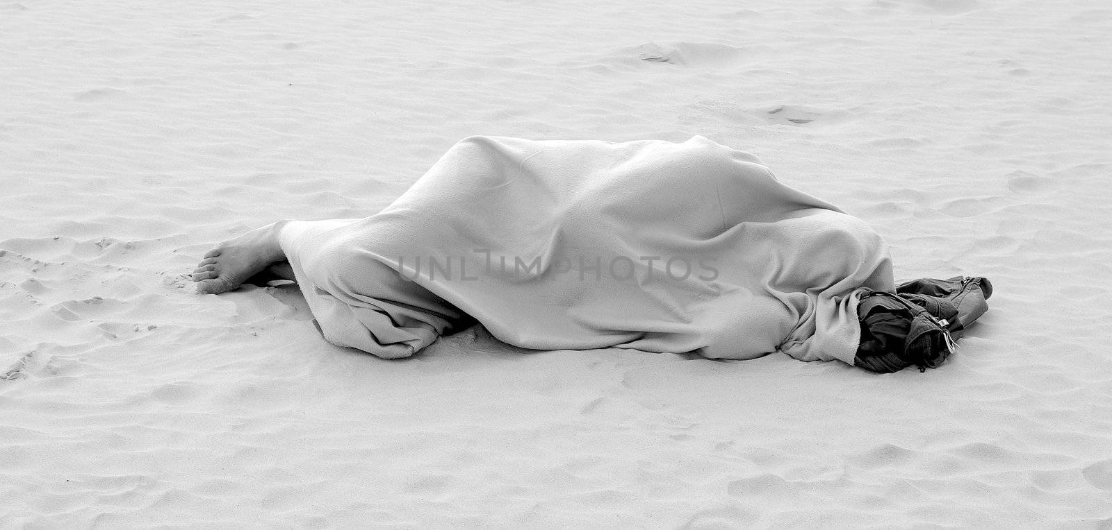Homeless man sleeping on sea beach, monochrome image