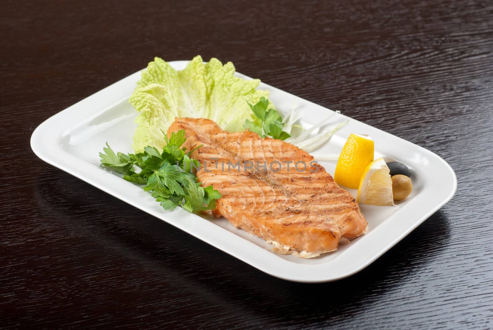 Grilled salmon steak with greens,onion, lemon, lime and olive