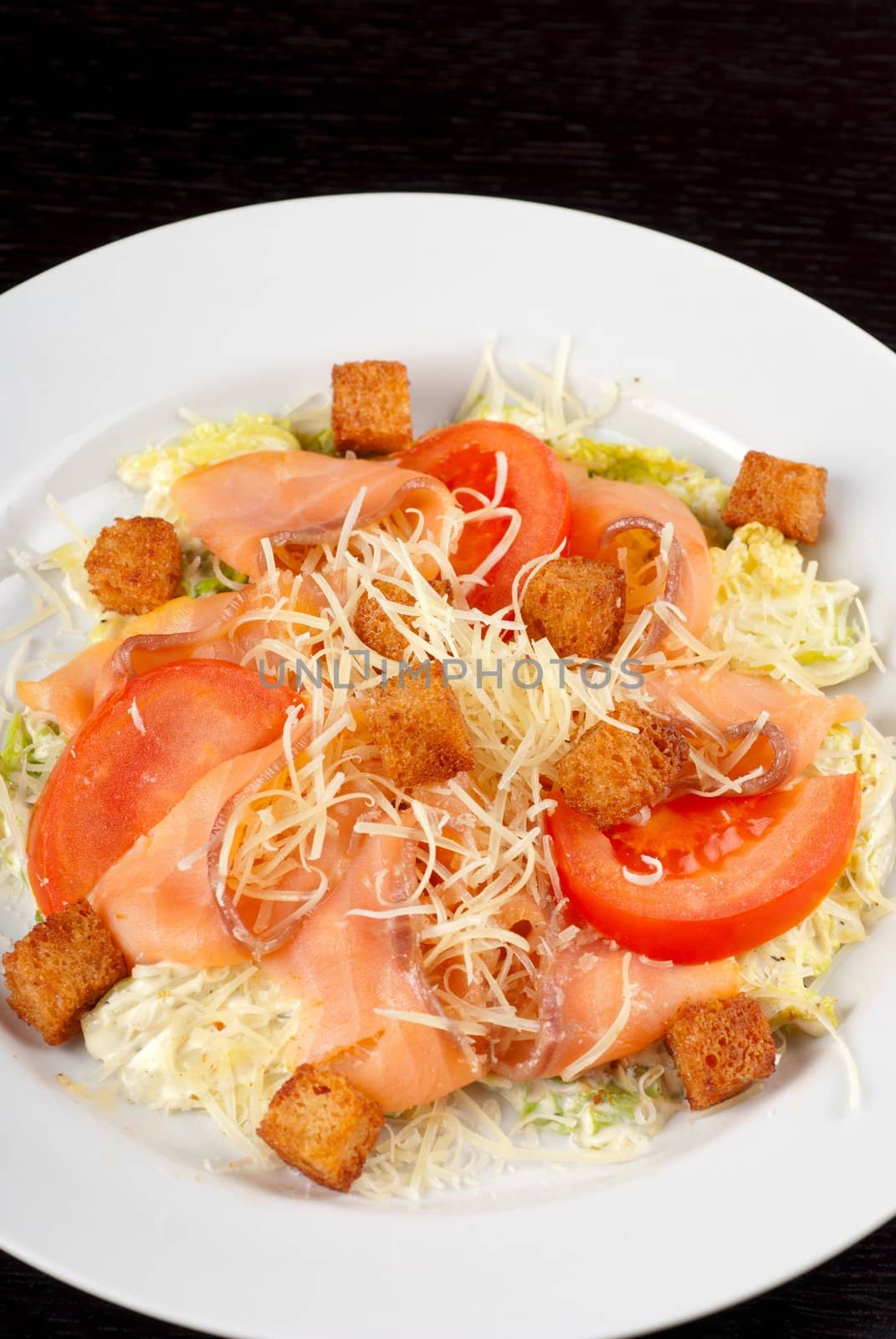 Salad of lettuce, chinese cabbage, tomato, garlic rusk, parmesan cheese, sauce and smoked salmon filet