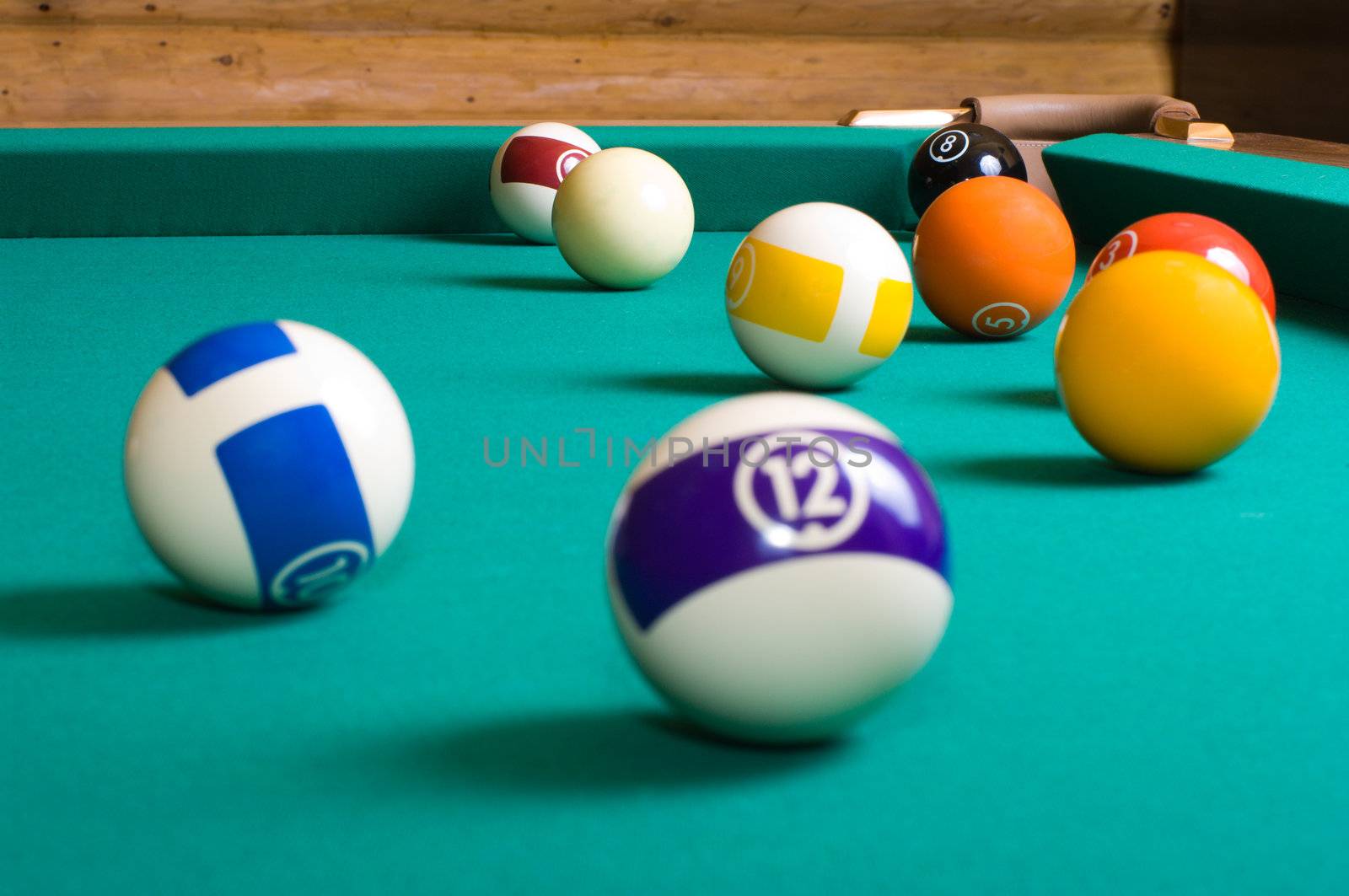 Balls for playing pool on a billiard table focus in the background.