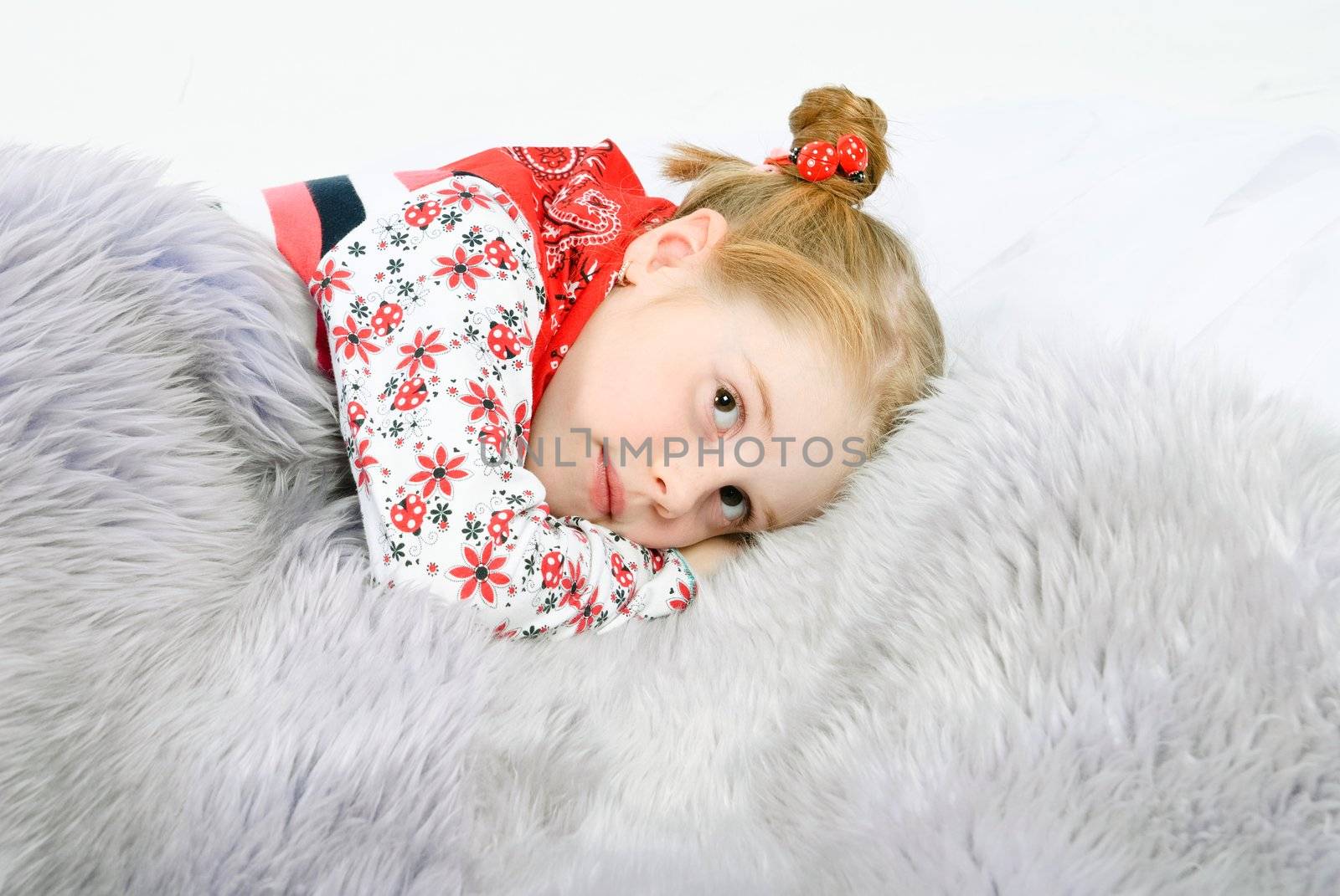 studio shot of pretty little girl lying on a fur