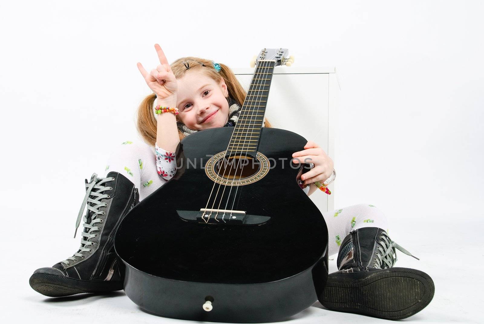 studio shot of pretty little girl playing black acoustic guitar