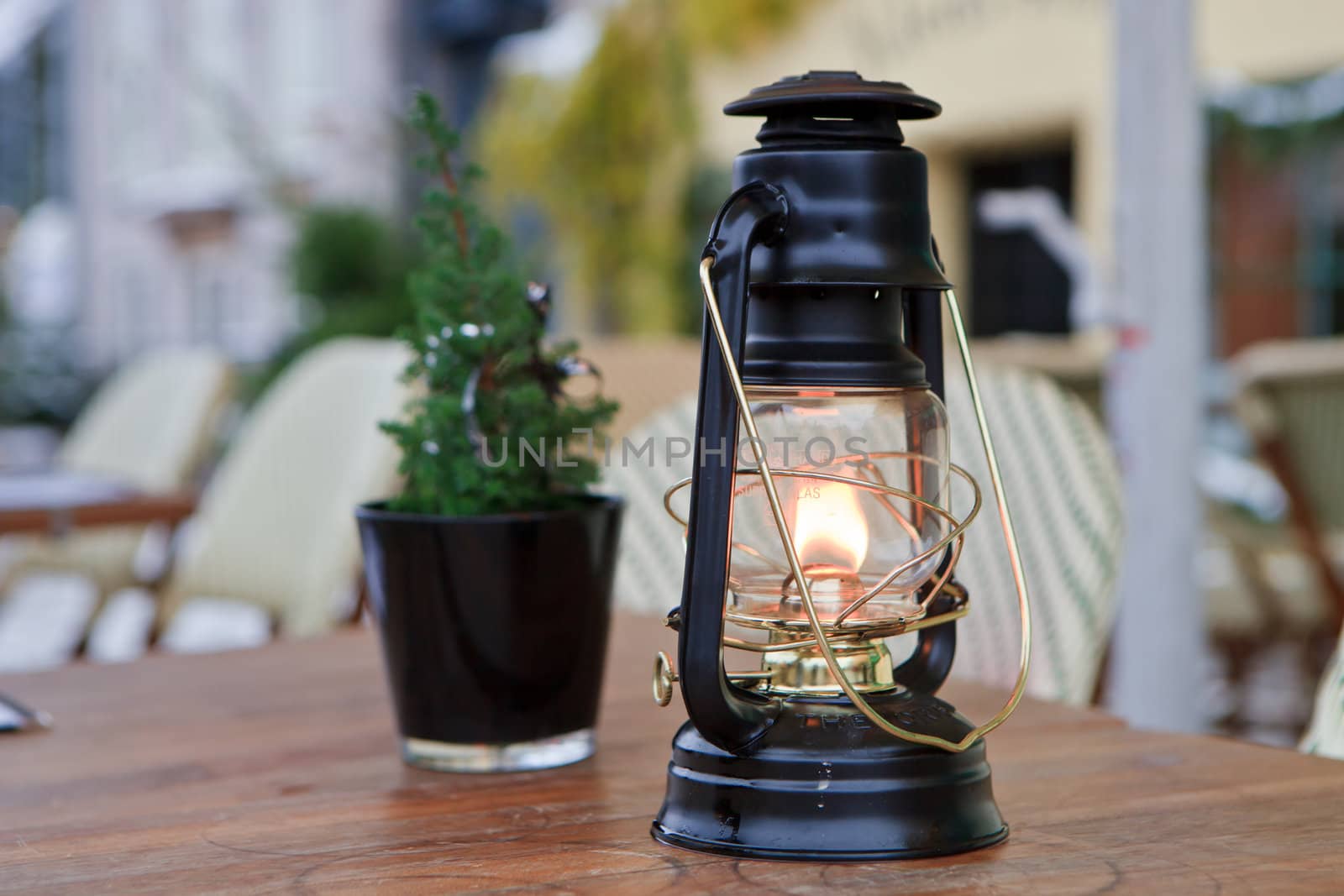 Burning black oil lamp on a table with a minature Christmas tree