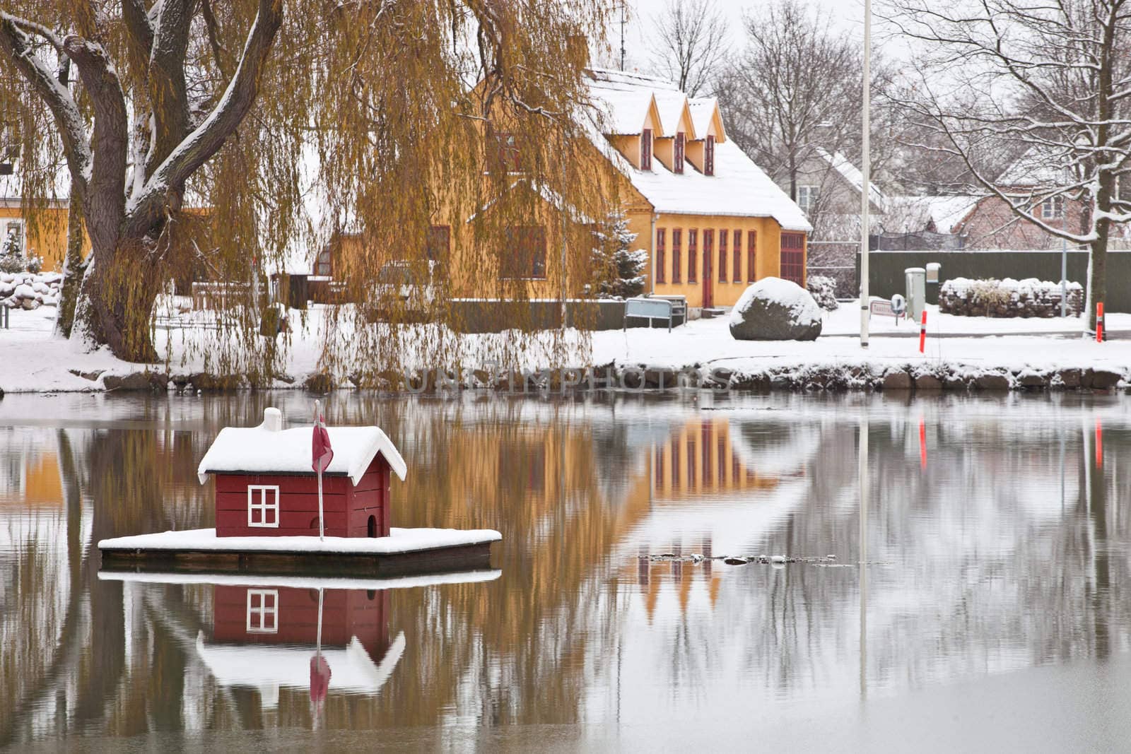 Minature snow covered house floating on a pond