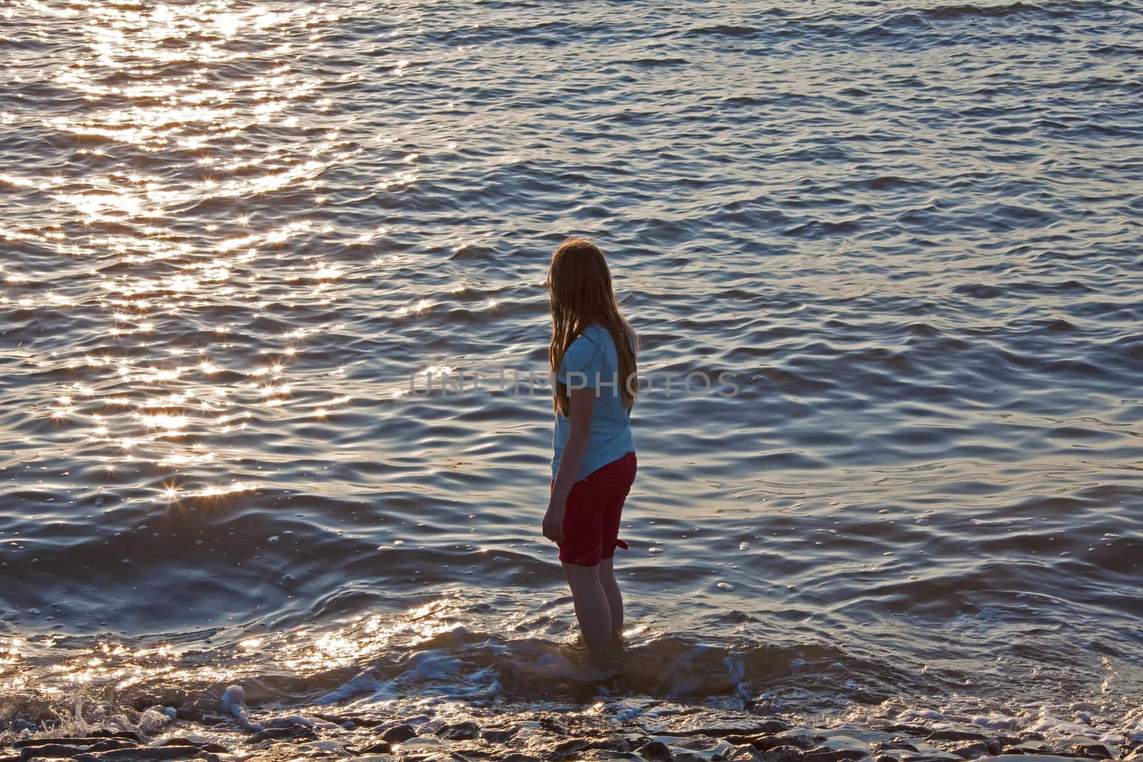 This image shows a girl at sea in the evening sun