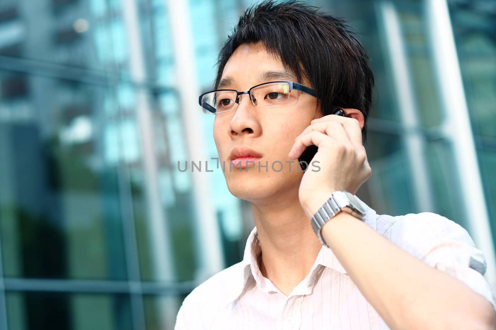 casual asian businessman talking on his cell phone  by cozyta