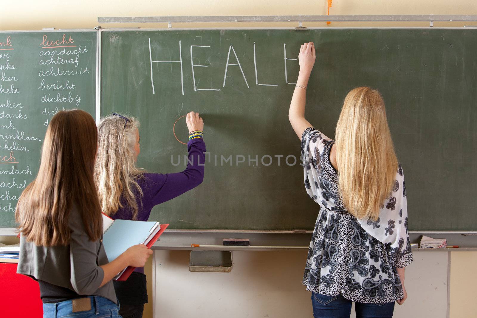 Two students together with the teacher preparing the blackboard