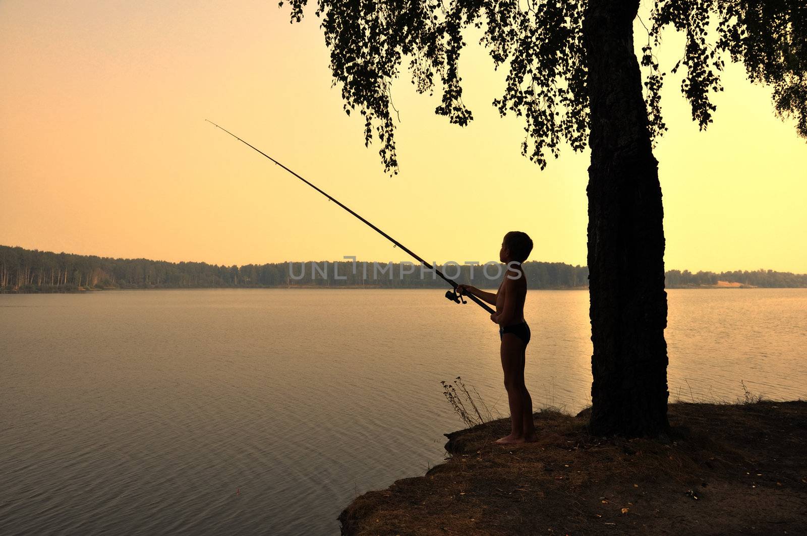 silhouette boy fishing on sunset on river