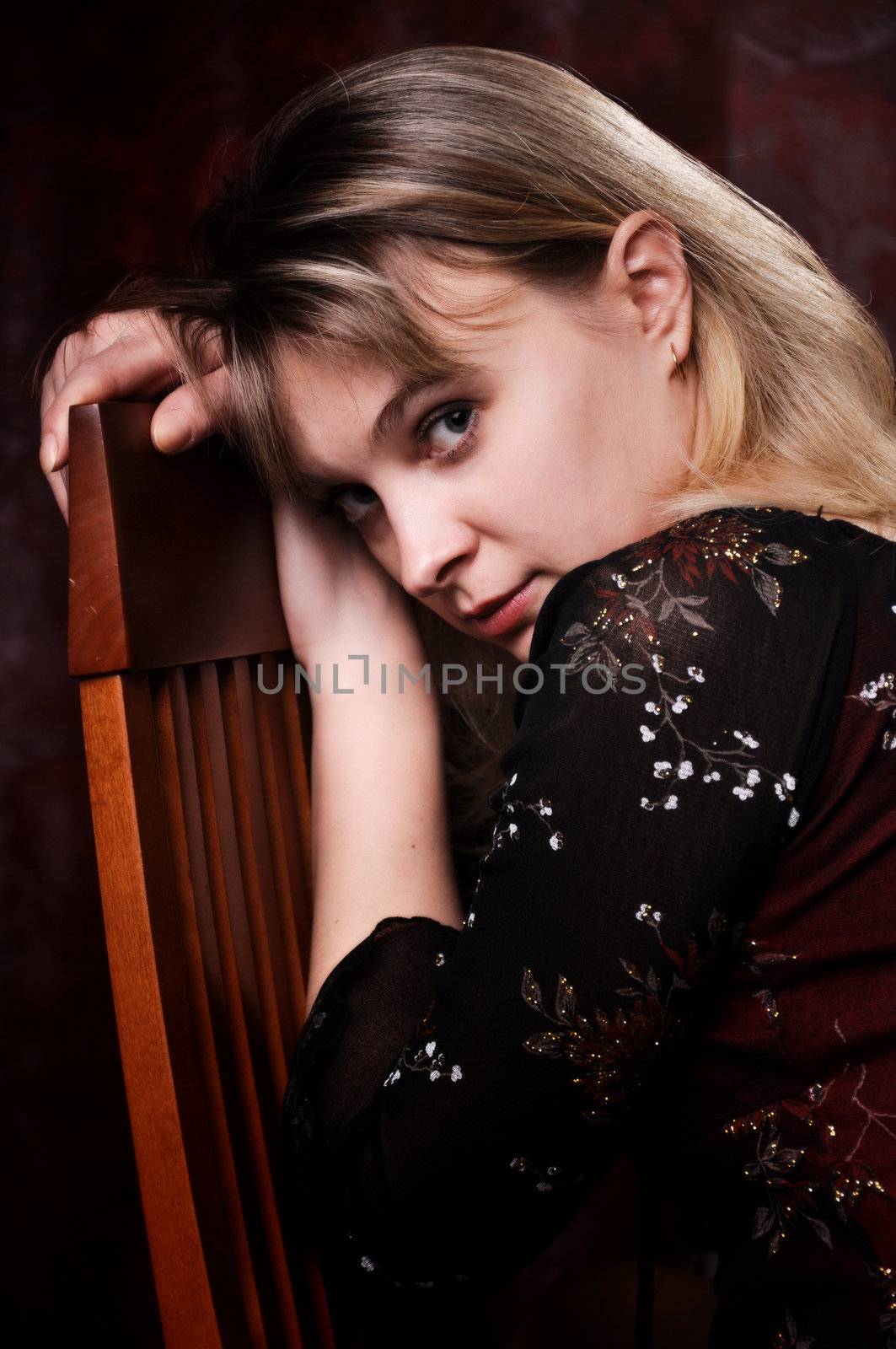 young woman is sitting on a chair and looks into the camera