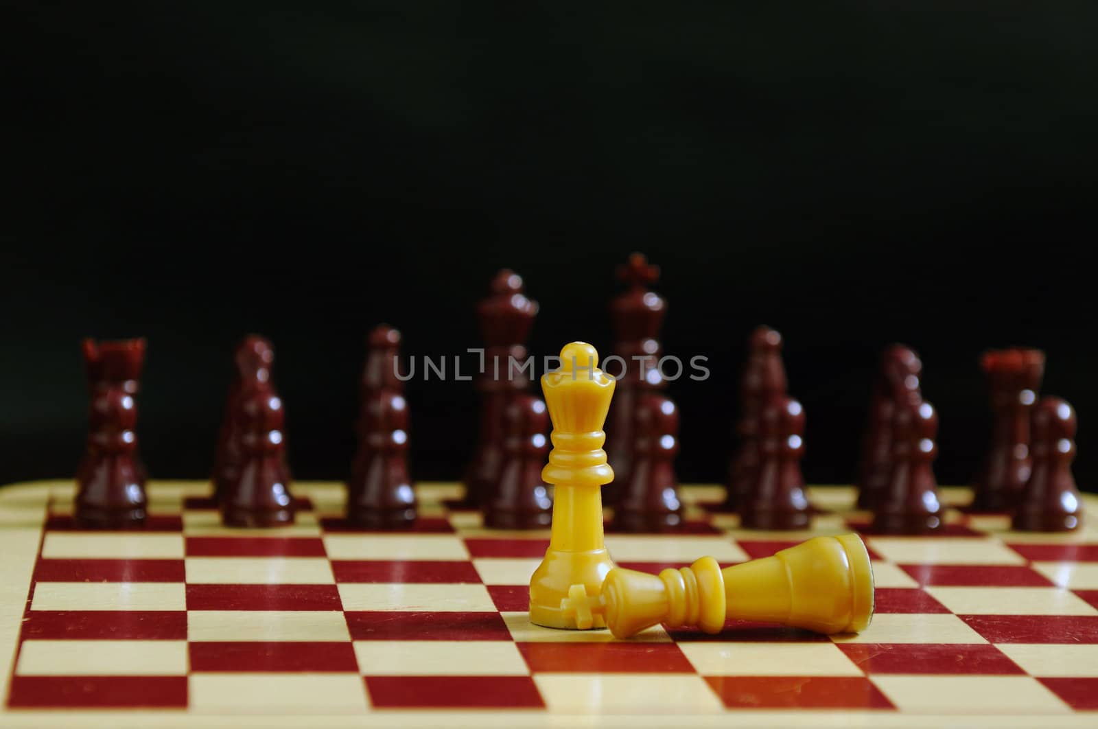 King fallen at the feet of queen in a chess game