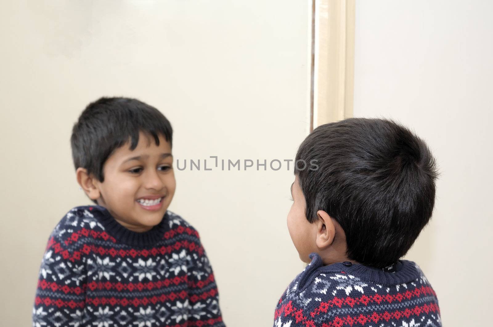 Cute toddler looking into mirror, laughing 
