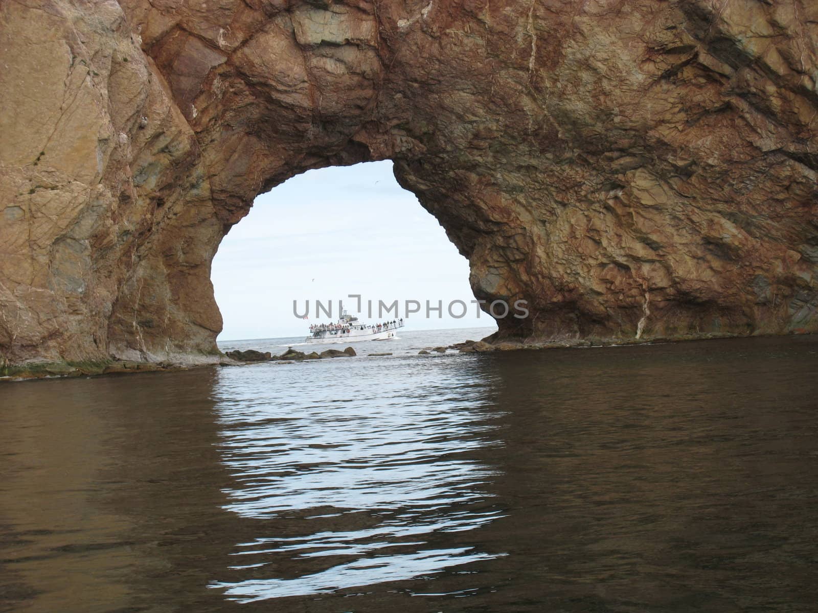 perce rock hole with a boat crossing, in Gaspesie, Quebec