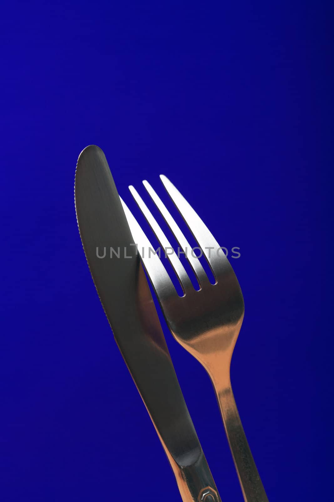 Extreme closeup of fork and table knife on blue background