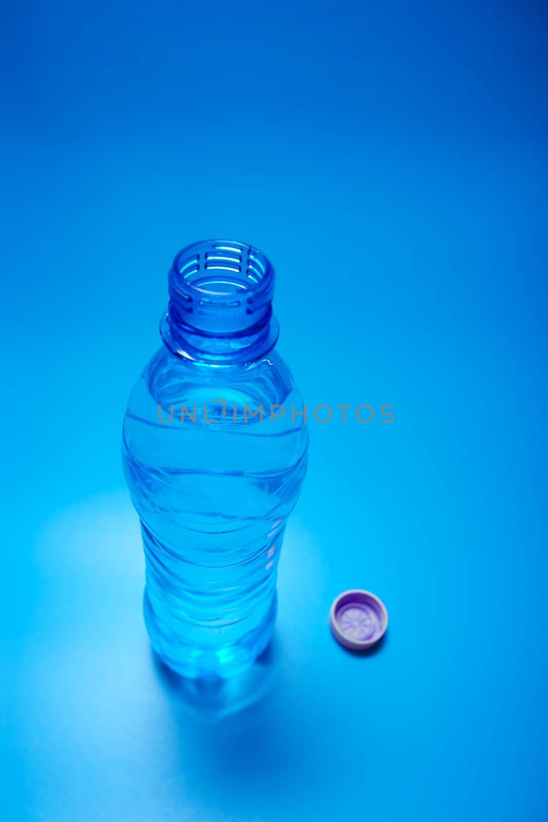 Open bottle of water on blue background