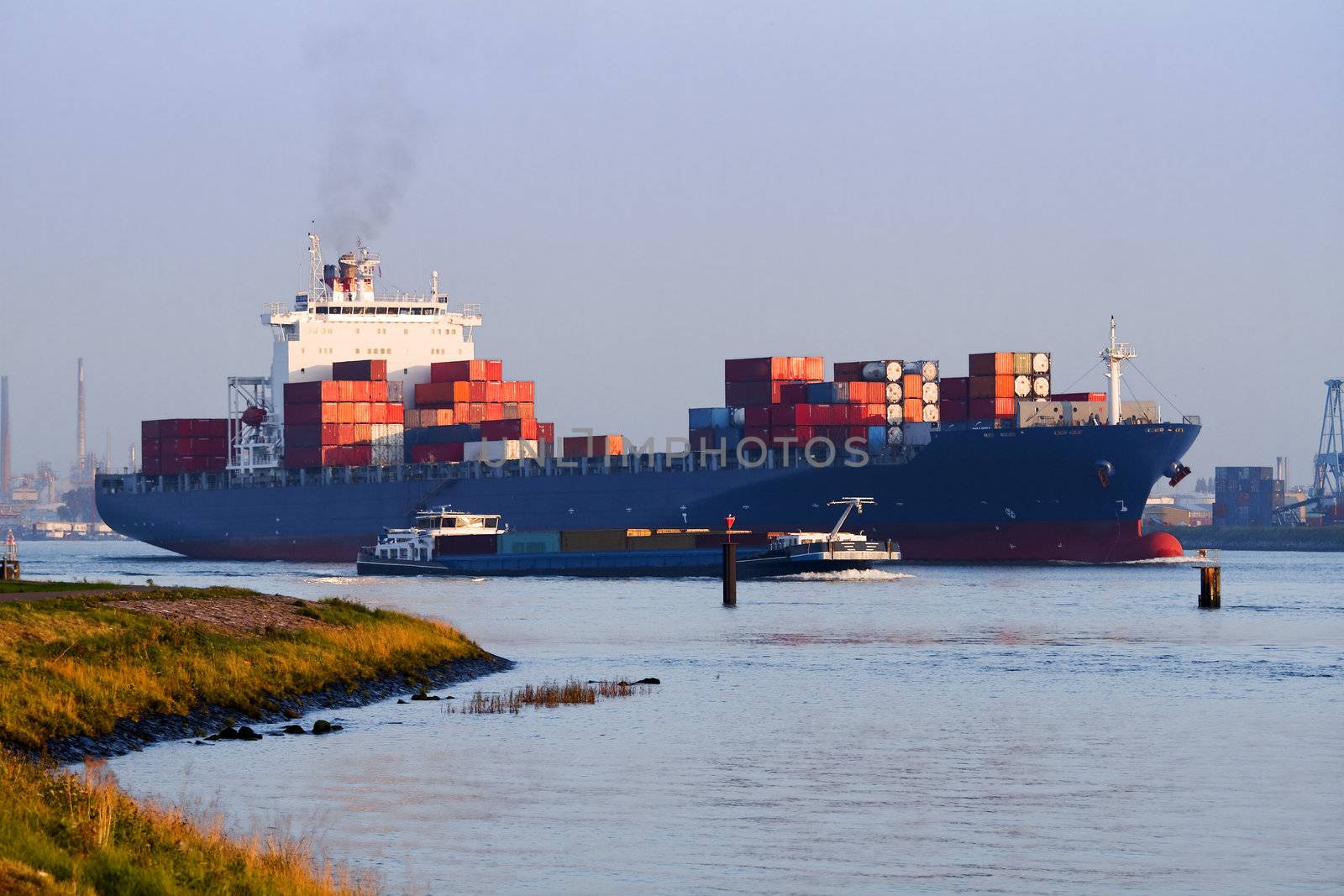 Big container ship on the river leaving port by evening light