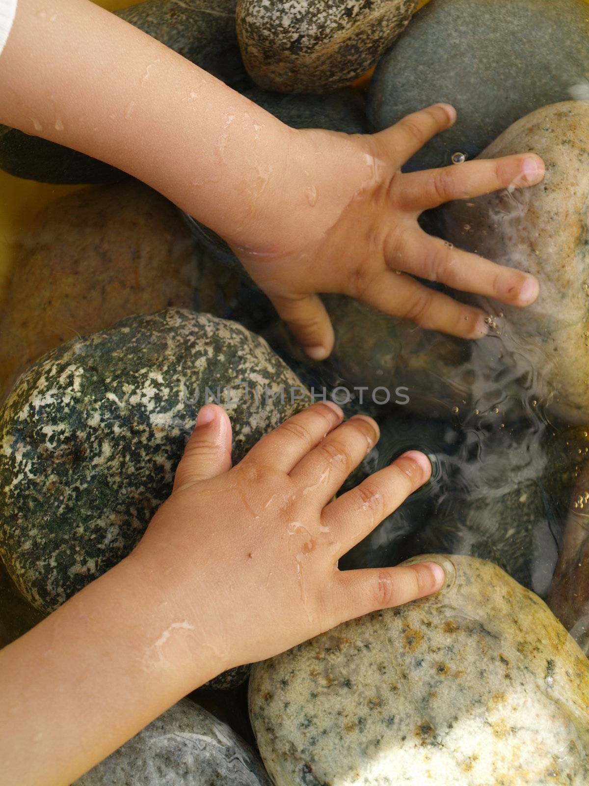 small hands playing with stones and water