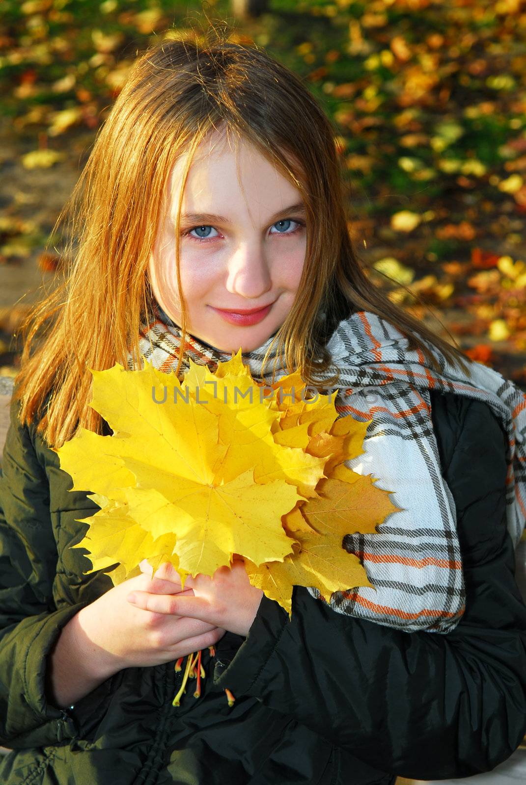 Portrait of a beautiful teenage girl with yellow fall maple leaves