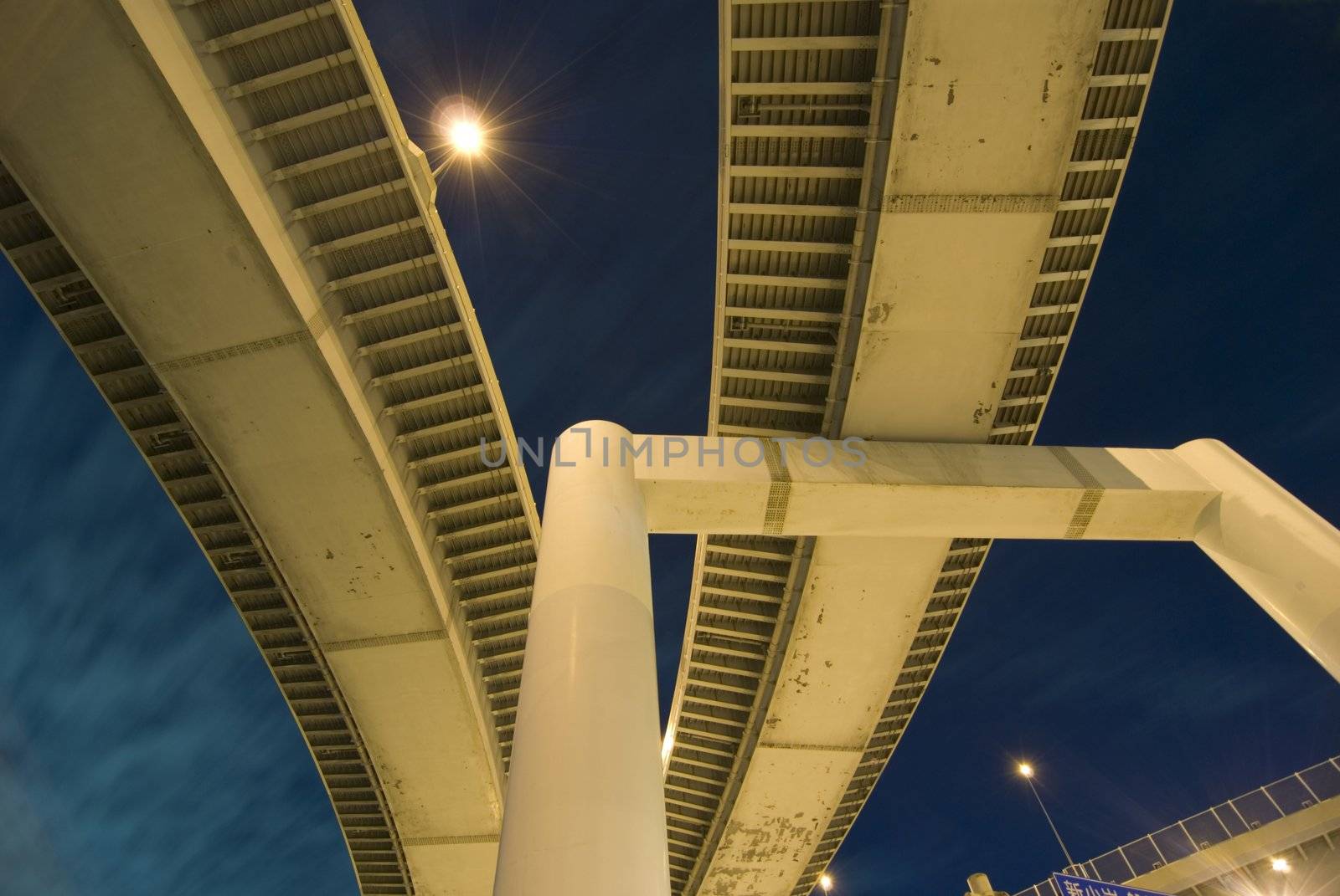 abstract image of modern powerful highway support and road structures over night sky and illuminations background, Tokyo, Japan