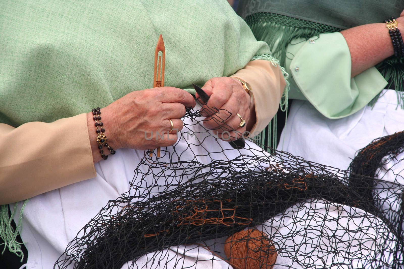 Woman showing traditional skill of repairing fishingnet