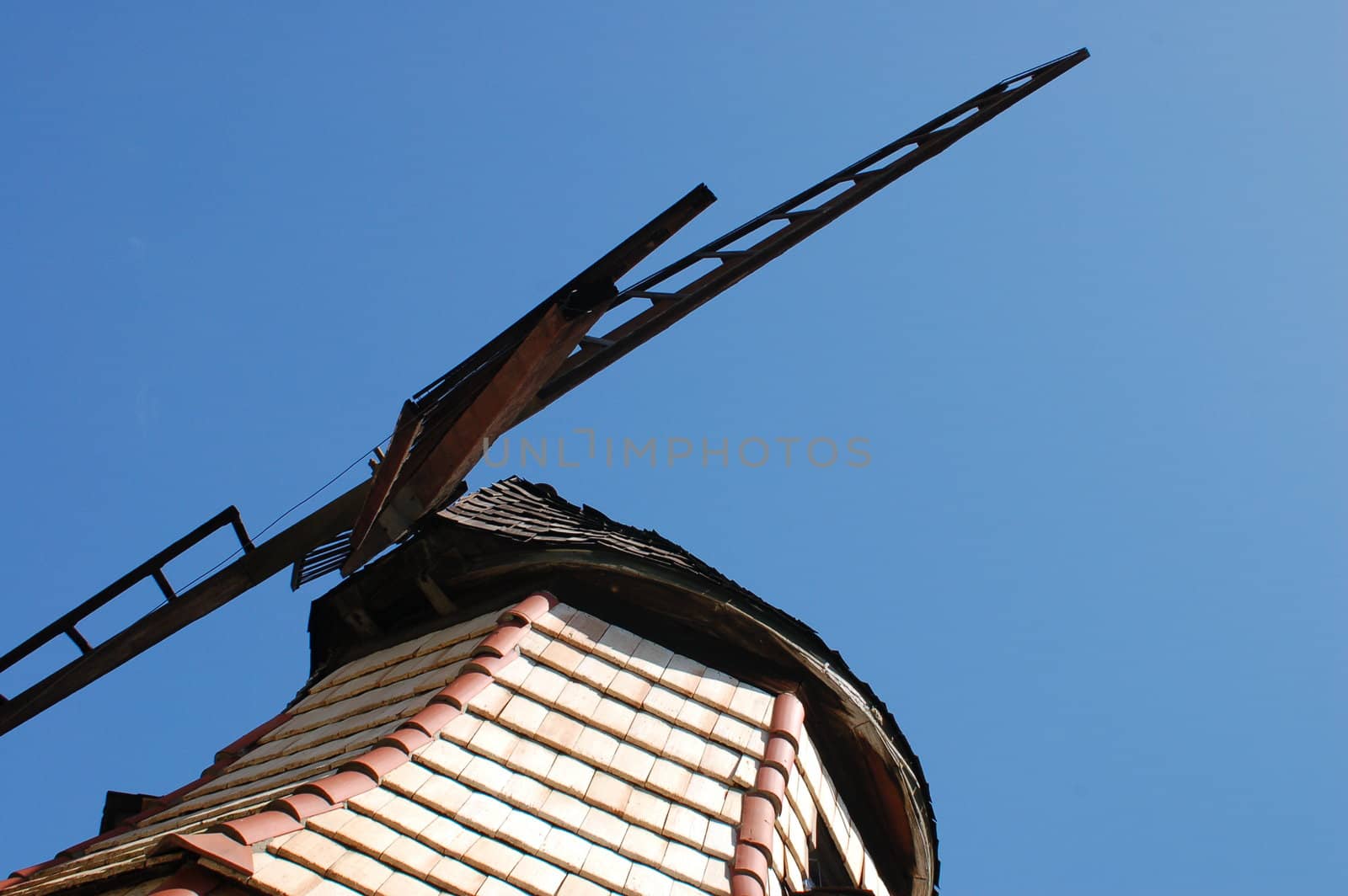 View of the blades of a windmill at The lake Shrine in California, against a bright blue sky.