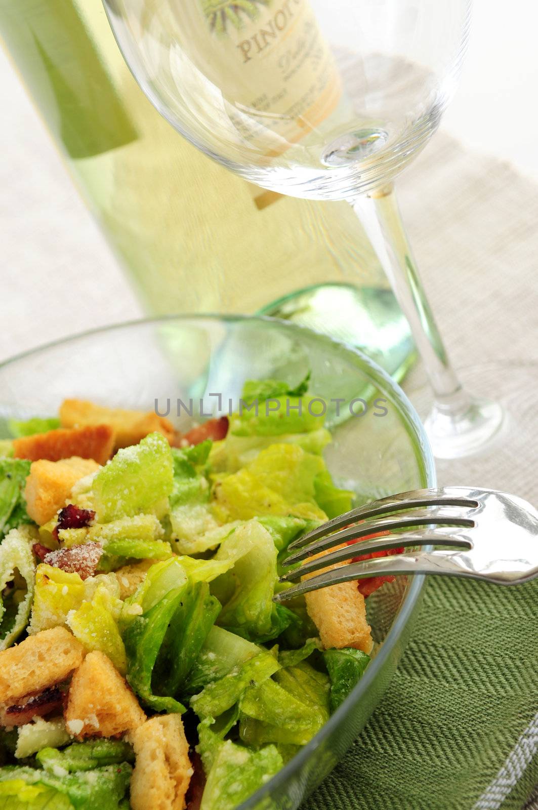 Caesar salad served in a glass bowl and white wine