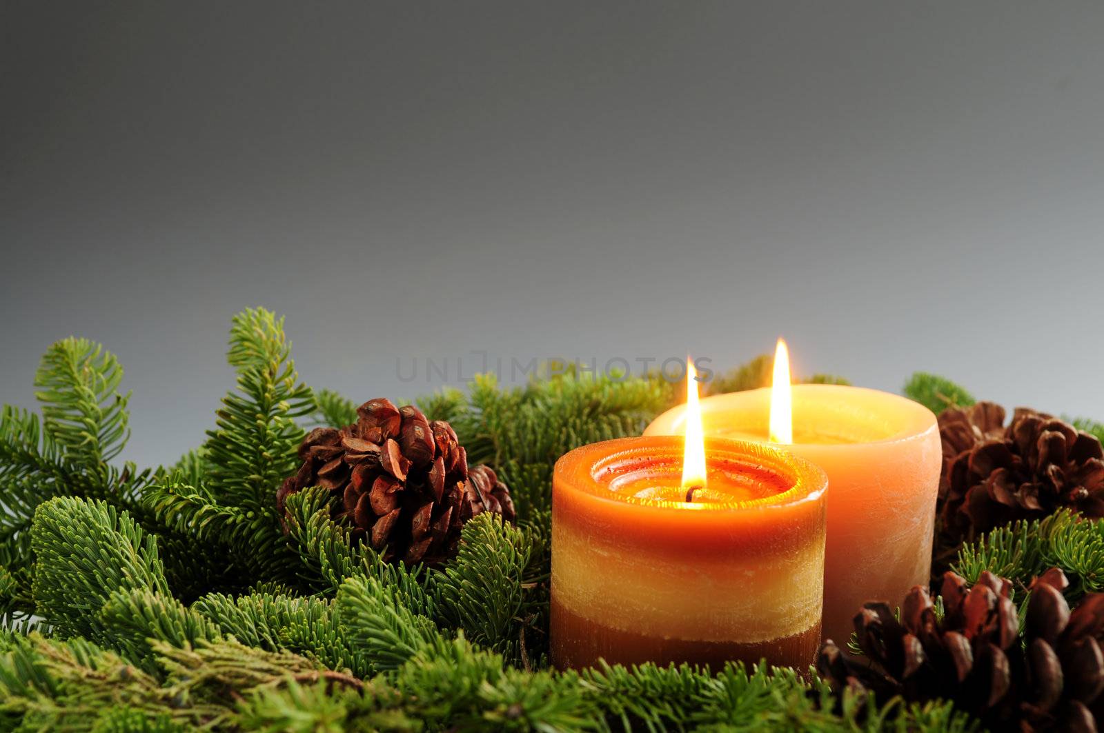 Christmas arrangement of burning candles and green spruce branches, background