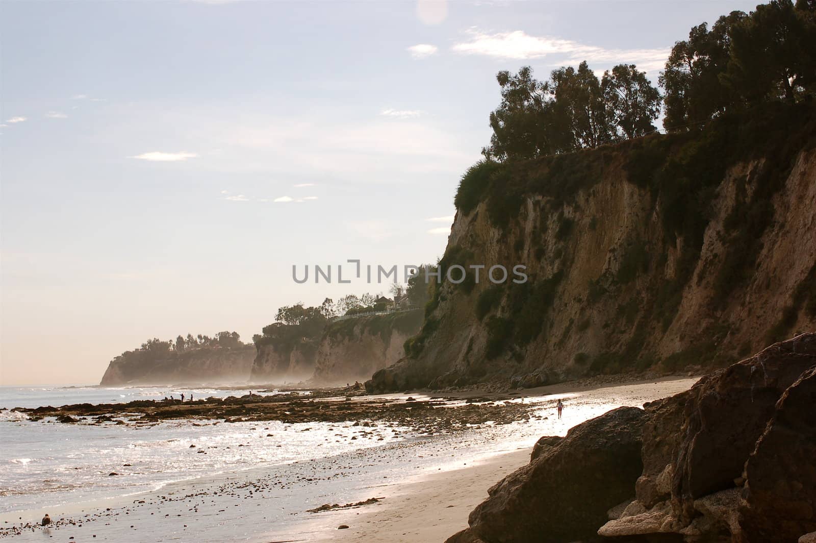 Daytime shot of the deeply curved cove at Paradise Cove in Malibu, Southern California.  Steep cliffs, trees, sand and ocean.