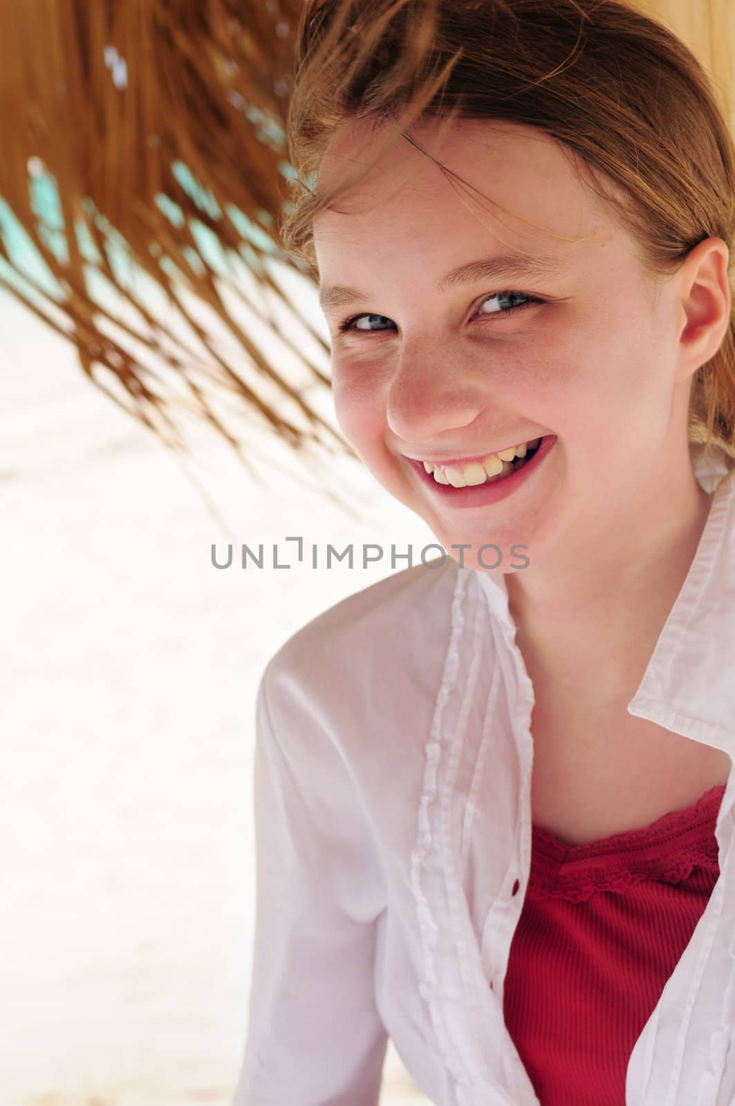 Portrait of a young girl on tropical beach under umbrella