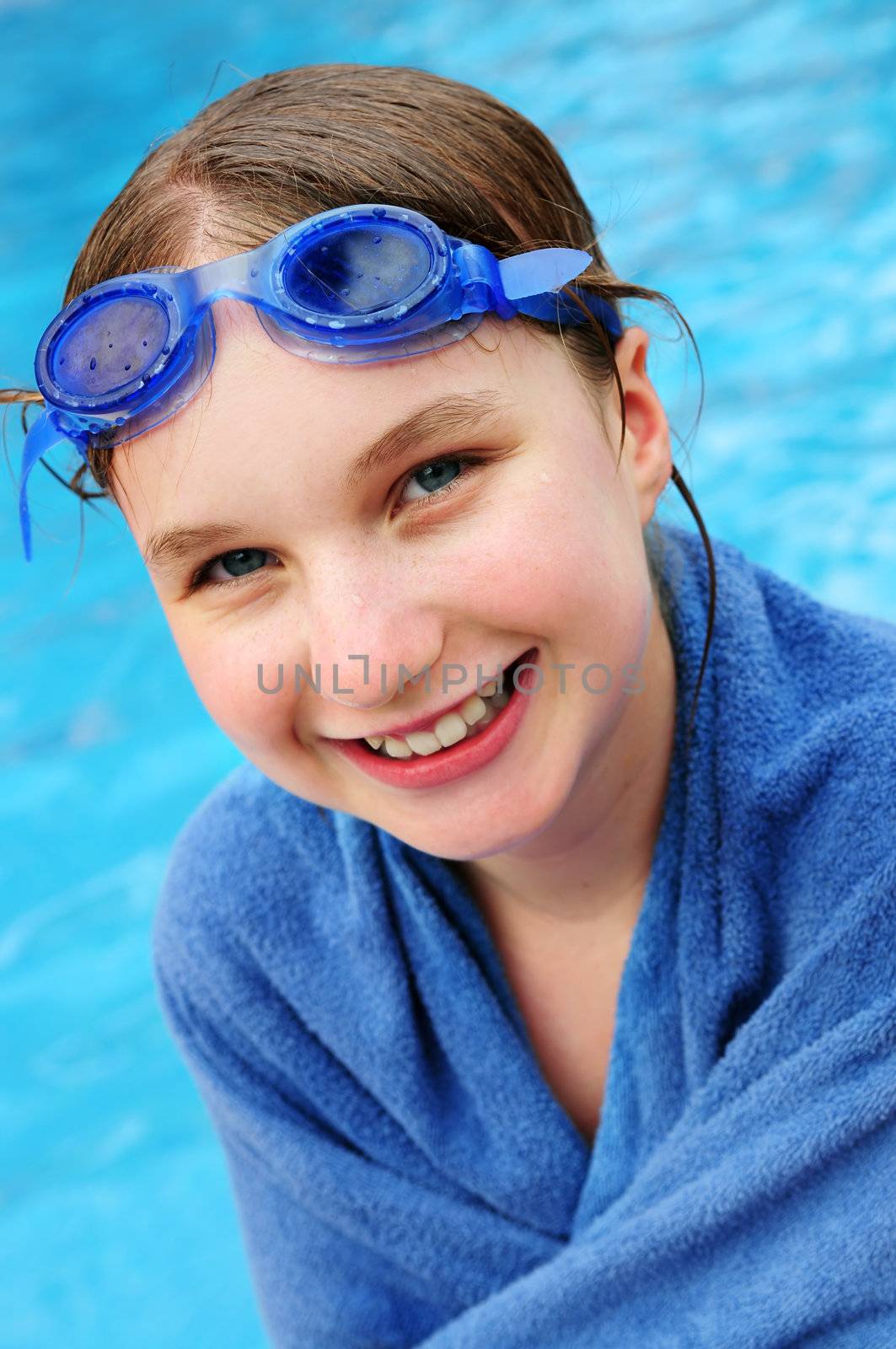 Teenage girl at the swimming pool wrapped in blue towel