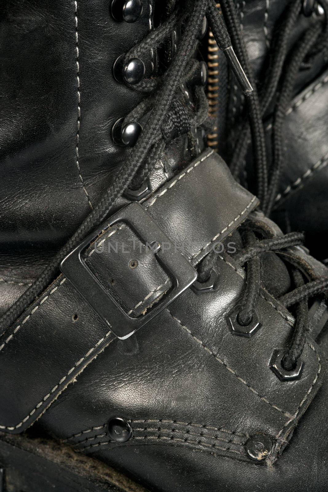 Background image of well worn, dirty, scuffed black boots.
