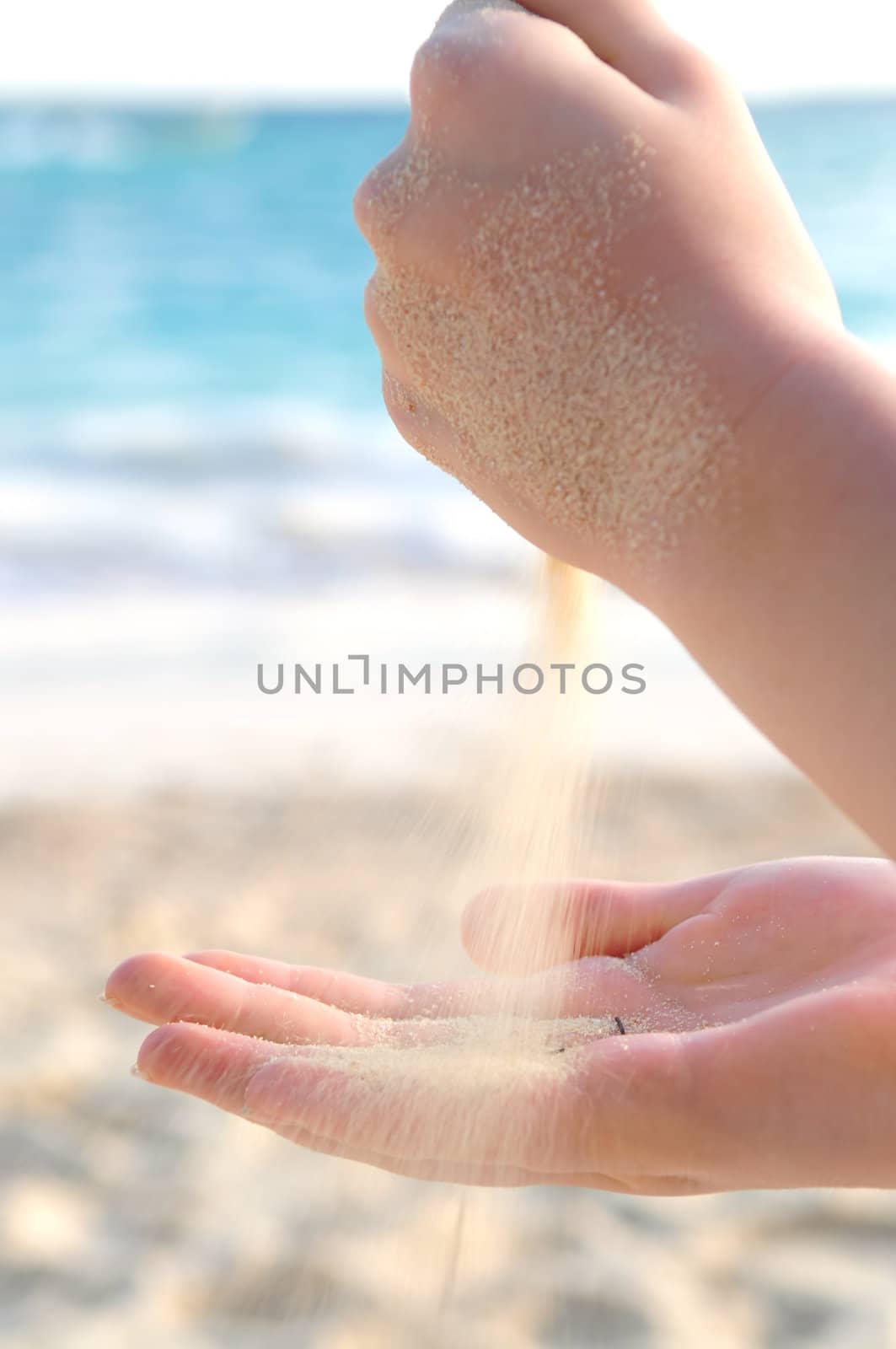 Hands pouring fine sand on a beach