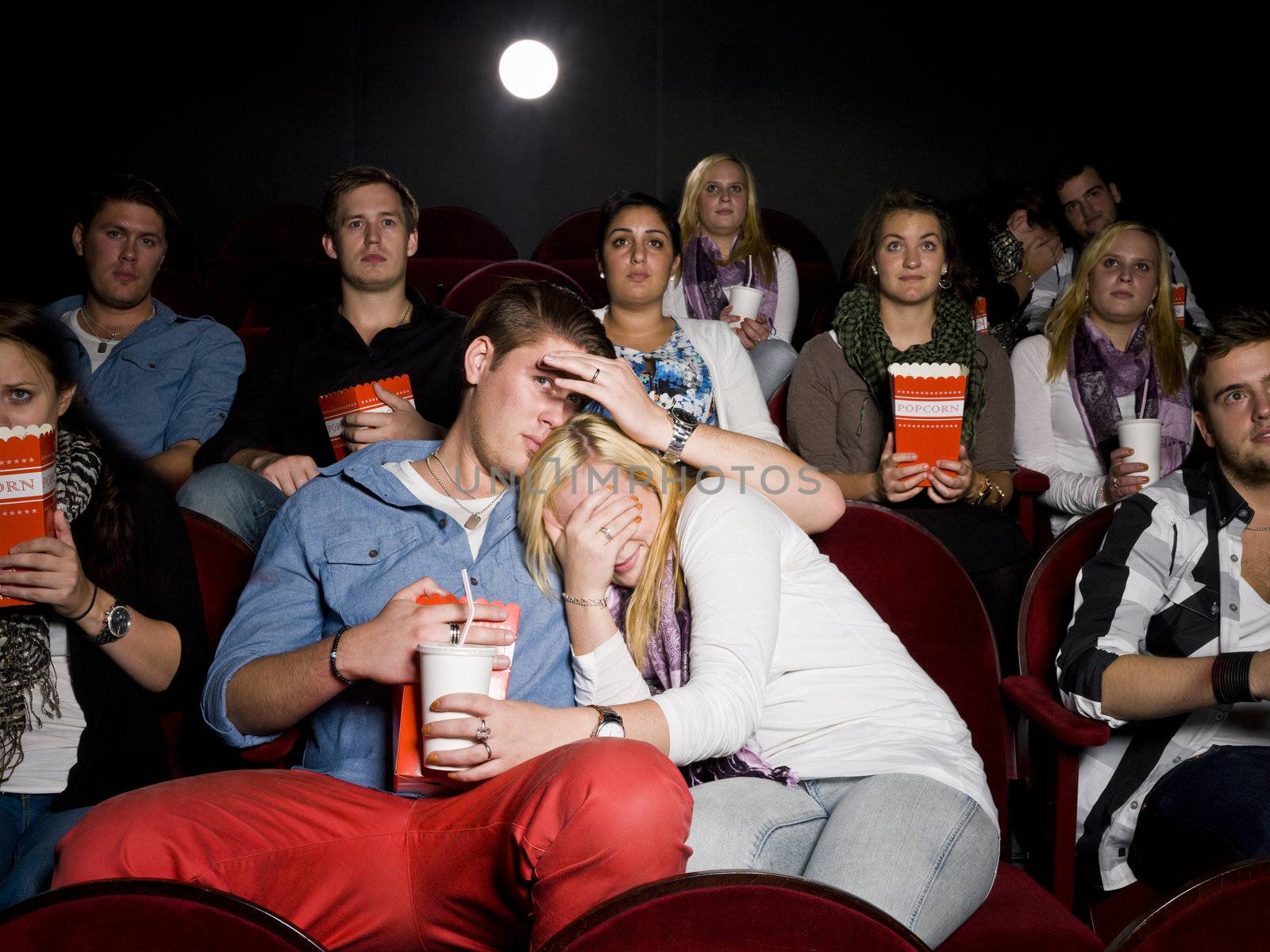 Young Scared Couple at the Movie Theater eating popcorn