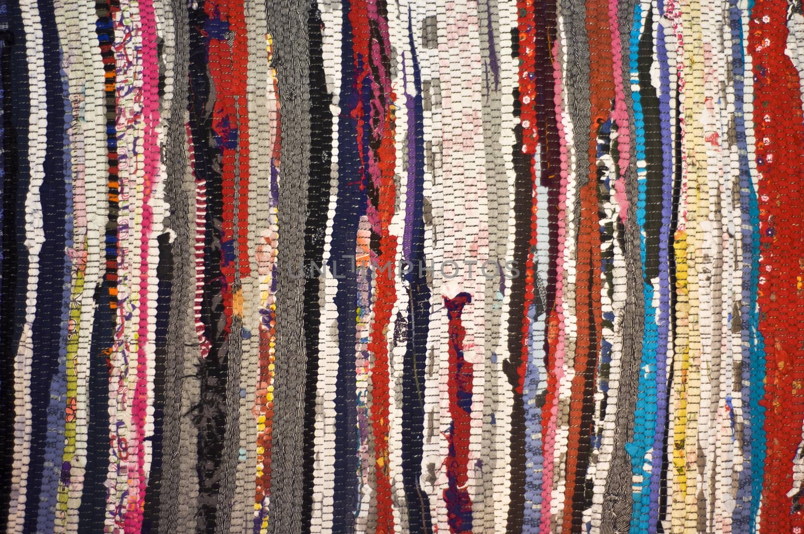 Multicolored rug, made of different pieces. Frontally, a fragment, closeup.