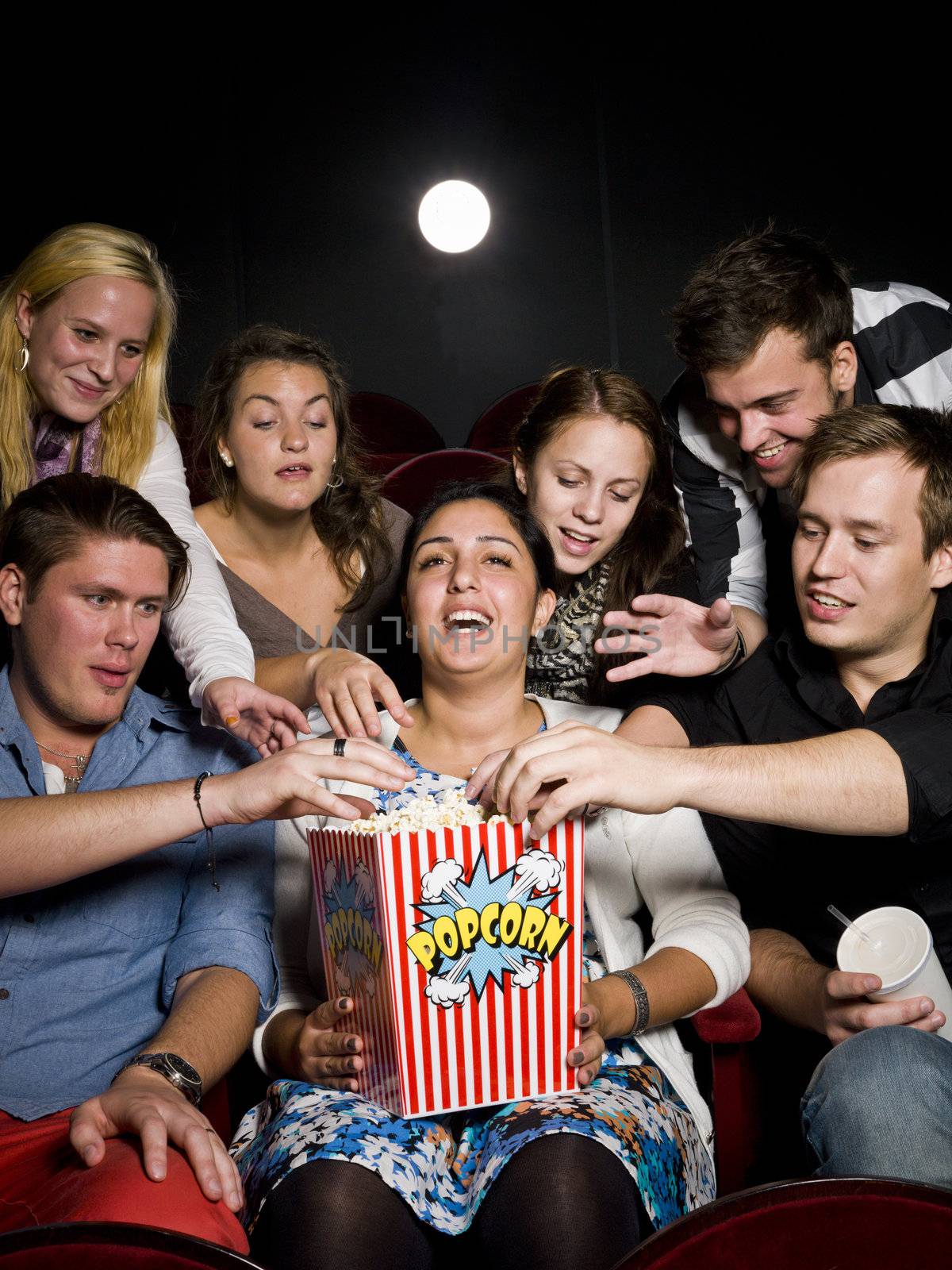 Group of young spectators eating popcorn at the movie theater