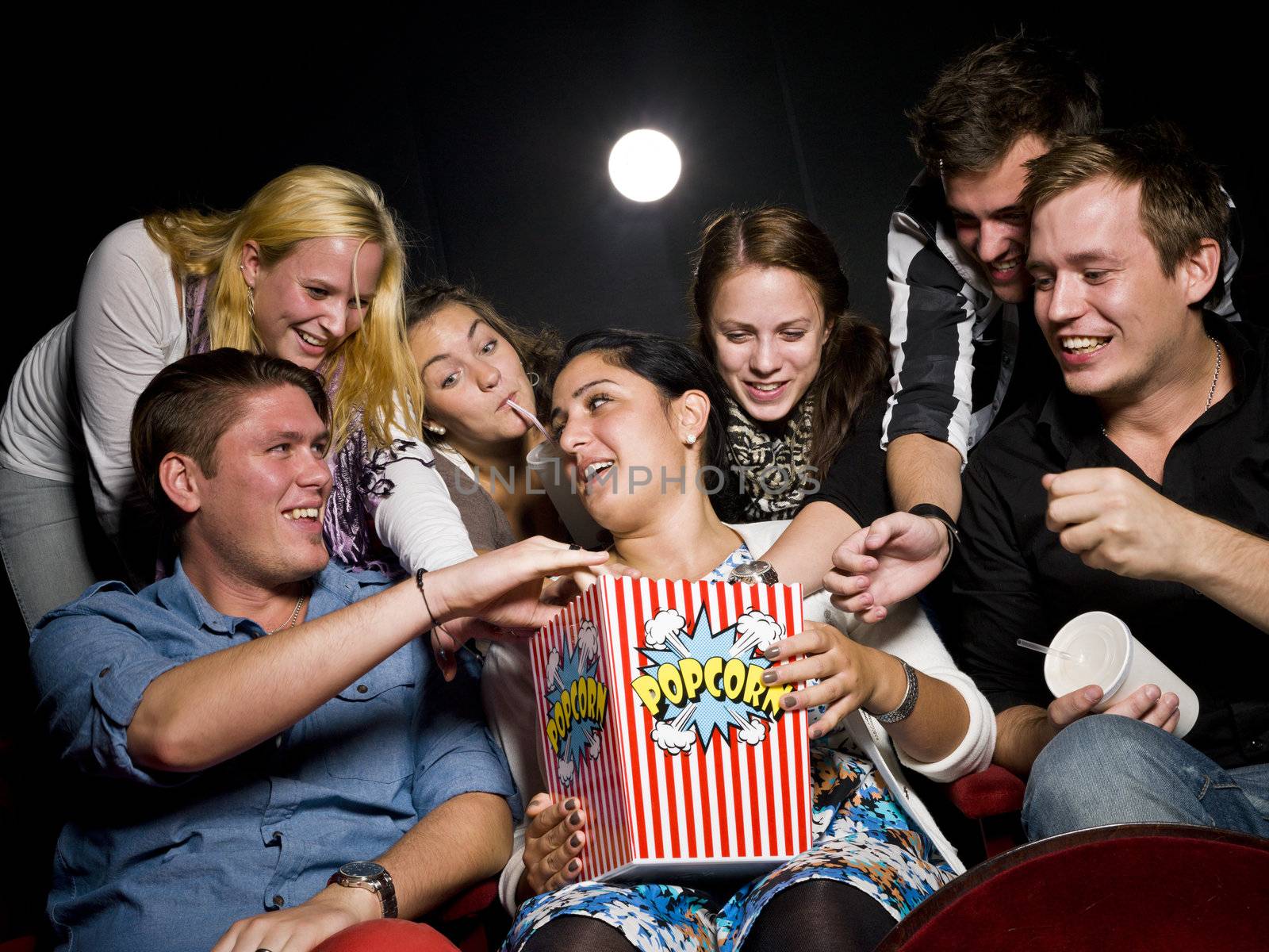 Group of young spectators eating popcorn at the movie theater